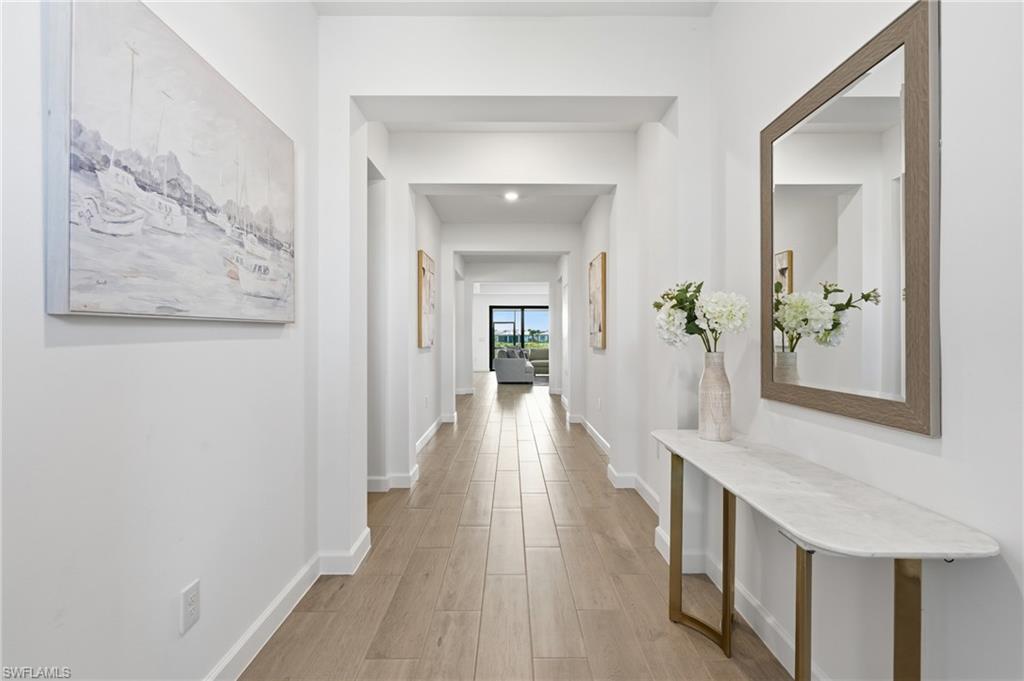 Bright hallway with wood-look tile flooring, a mirrored console table, and a view into the living area.