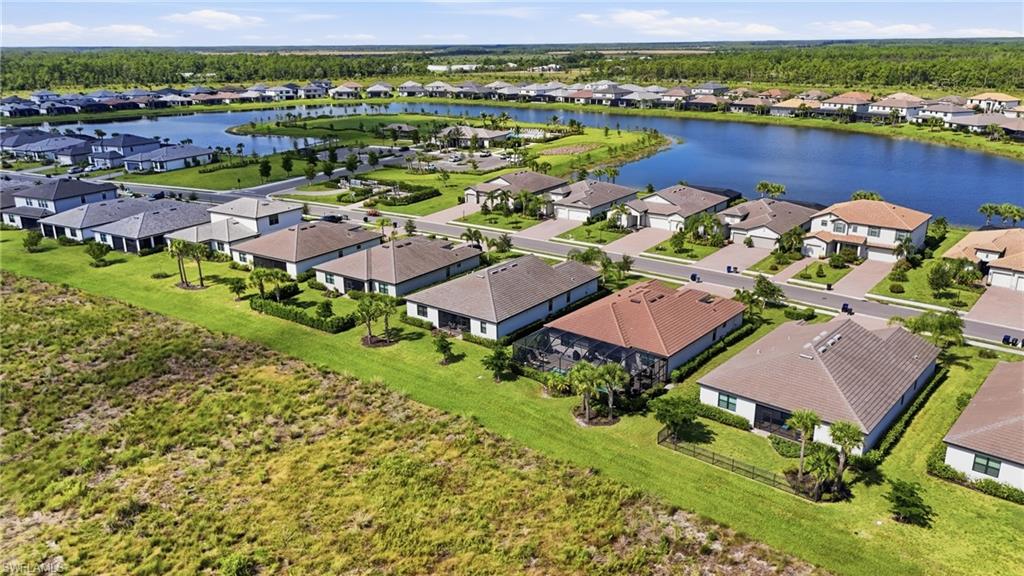 Aerial view of homes beside a lake, with open green land in the foreground.