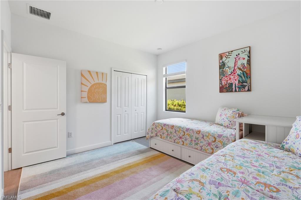Bedroom with two twin beds, floral bedding, and a colorful striped rug.