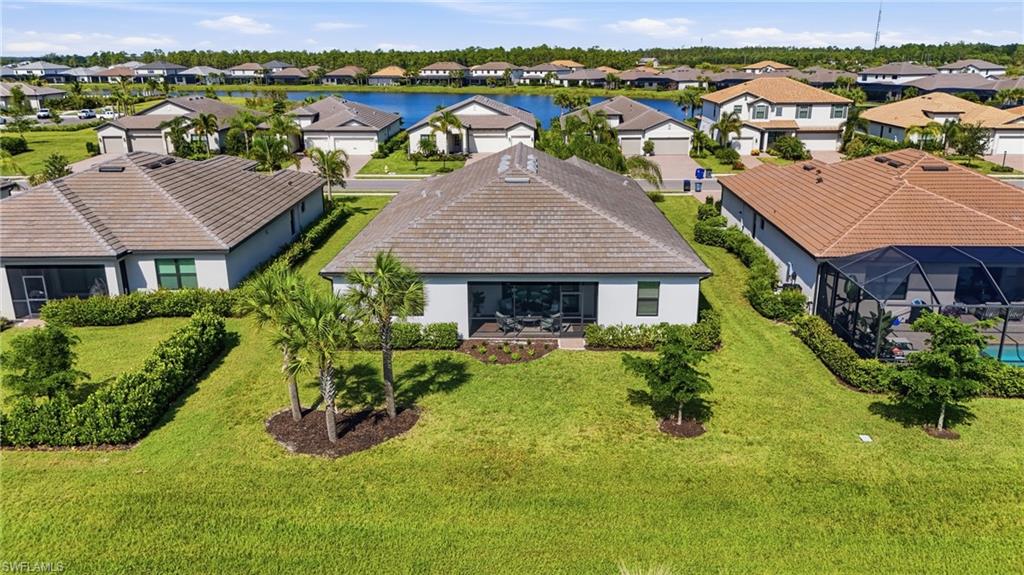 Aerial rear view of a single-story home with a broad gray roof and palm-planted backyard.