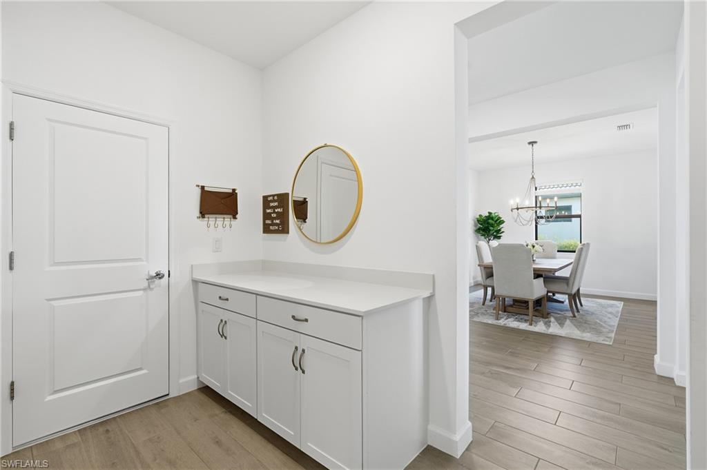 Entryway with built-in white storage cabinet and round mirror, opening to a furnished dining room.