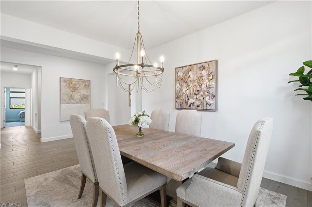 Dining room with a wood table, upholstered chairs, and a decorative chandelier.