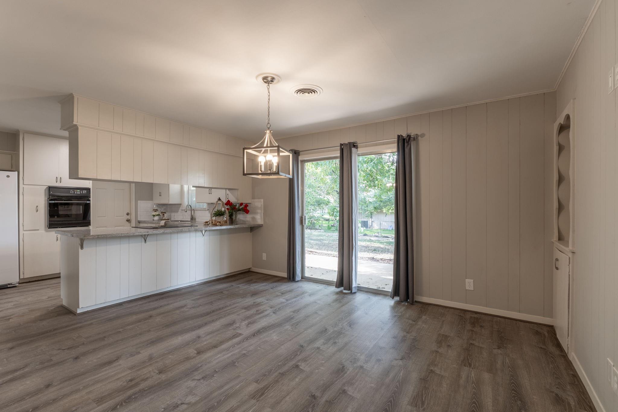 Open kitchen and dining area with white cabinetry, a peninsula counter, and sliding glass doors to the yard.