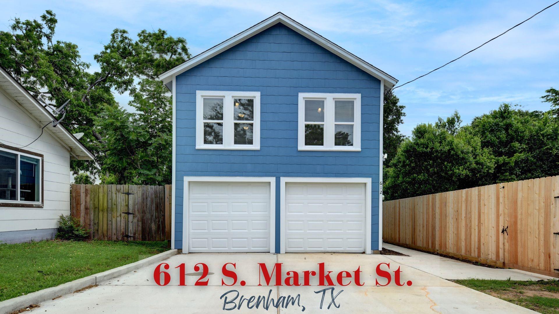 Blue two-story house with white trim, twin garage doors, and a fenced concrete driveway.