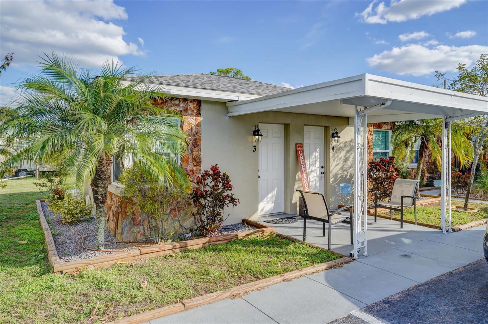 Single-story home with a covered porch, stone accents, and palm trees in front.