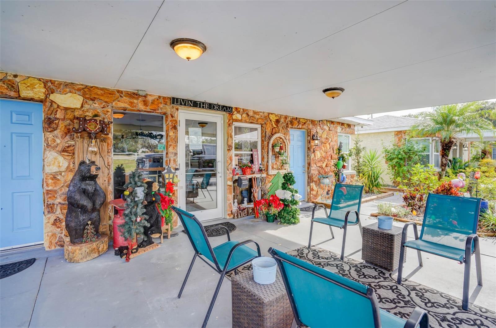 Covered patio with a stone facade, blue doors, turquoise chairs, and decorative bear statues.