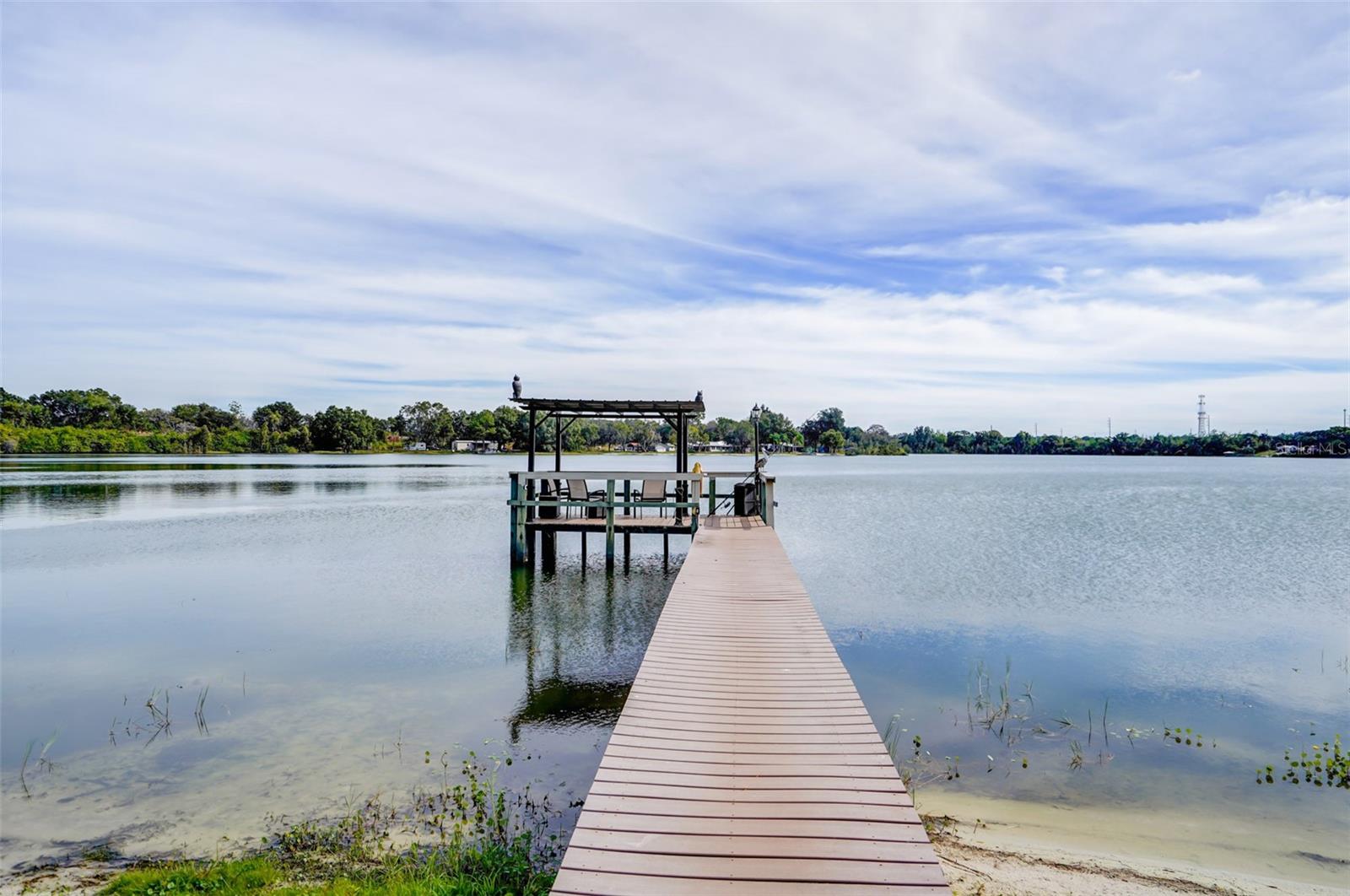 Boardwalk leading to a covered dock on a calm lake.