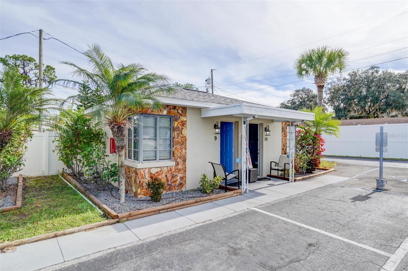 Small stone-accented building with entrances 9 and 10, palm trees, covered seating, and adjacent parking.
