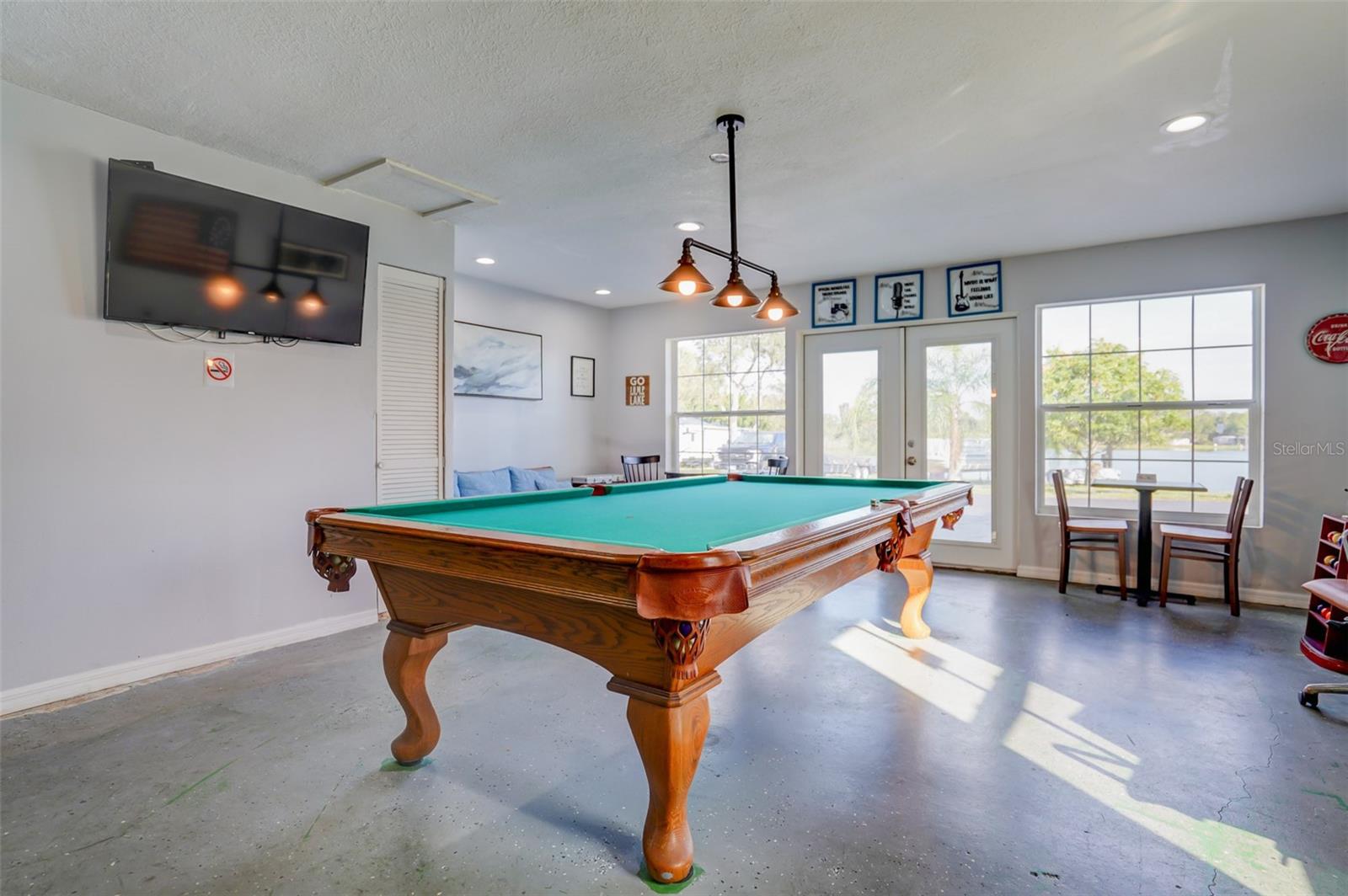 Game room with a wooden pool table and windows overlooking the water.