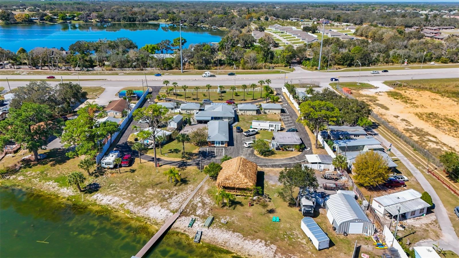 Aerial view of a developed property with multiple buildings, beside a lake and across from a highway.