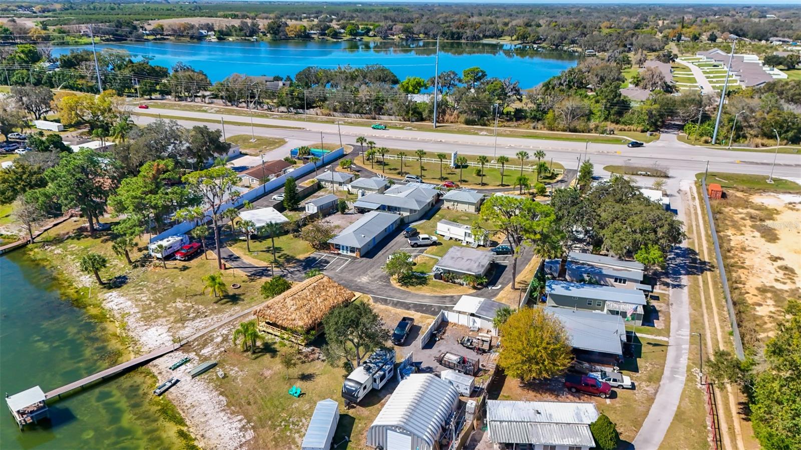 Aerial view of buildings beside a lake, with a highway across the upper side of the property.
