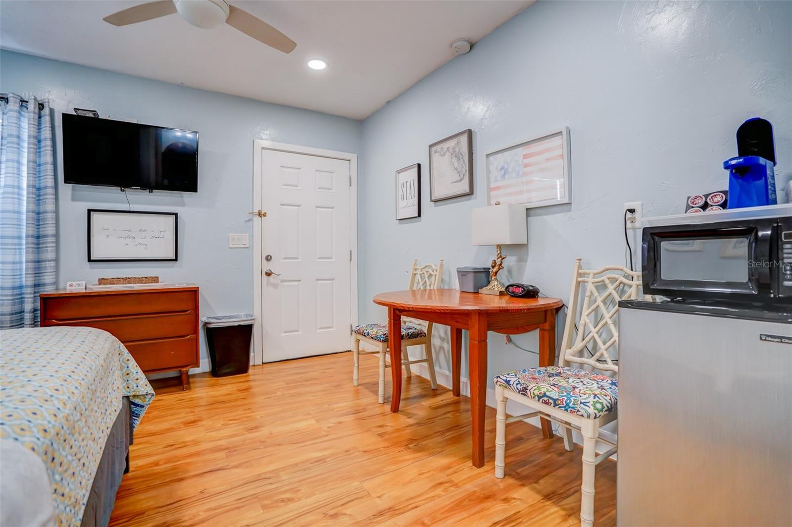 Furnished bedroom with a small dining table, wall-mounted television, and microwave.