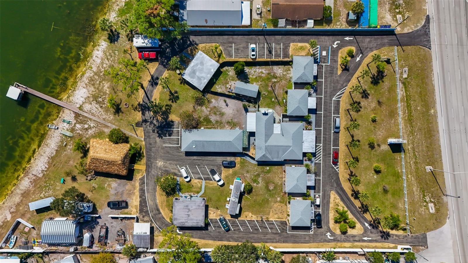 Aerial view of a multi-building property beside a lake, with parking and a dock.