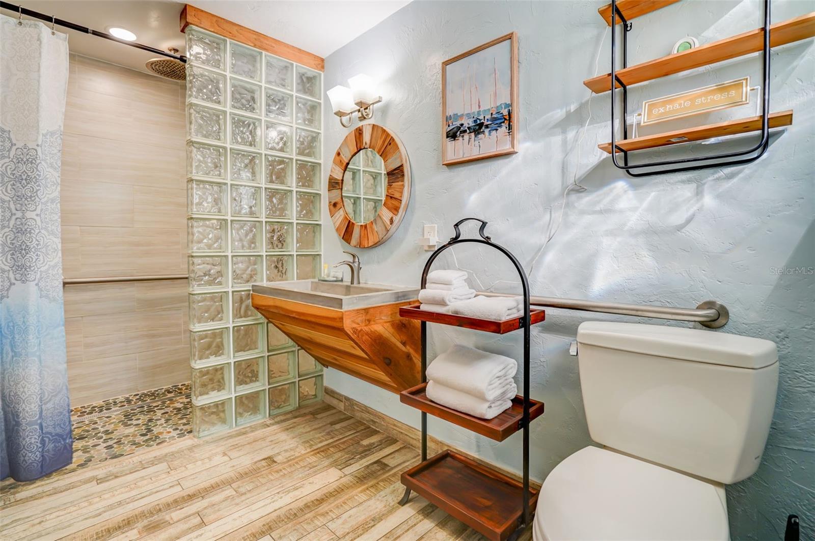 Bathroom with a glass-block shower divider and a wooden vanity with a vessel sink.