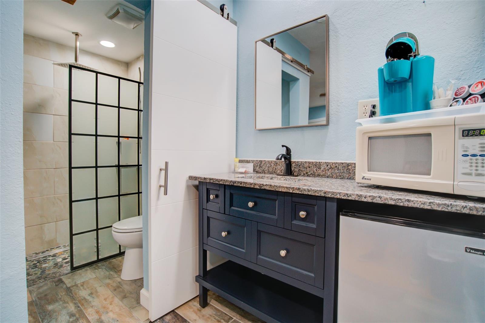 Bathroom with a dark blue vanity and black-framed glass shower enclosure.