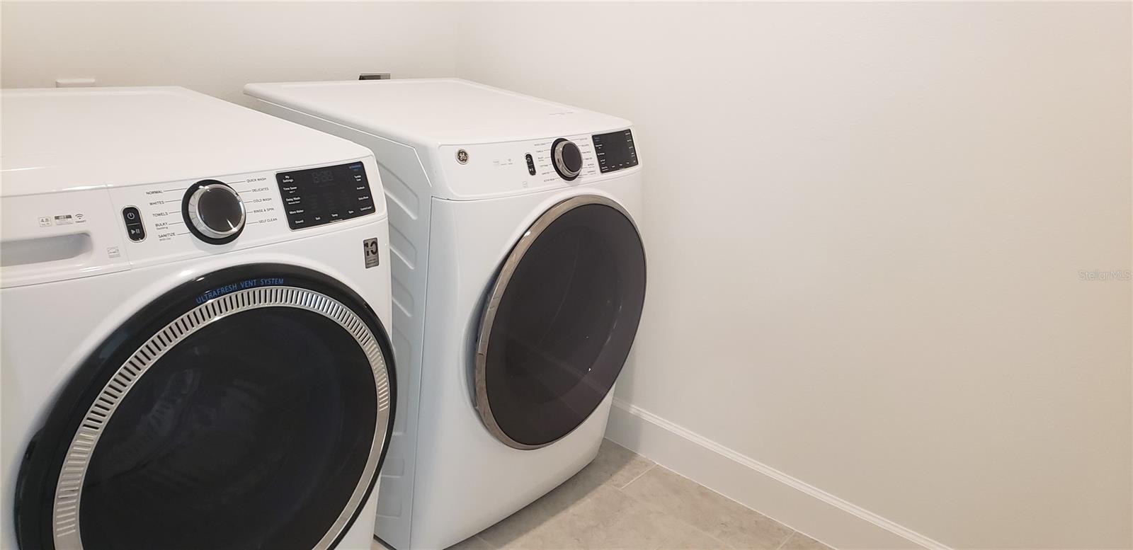 Laundry room with two white front-loading washer and dryer units.