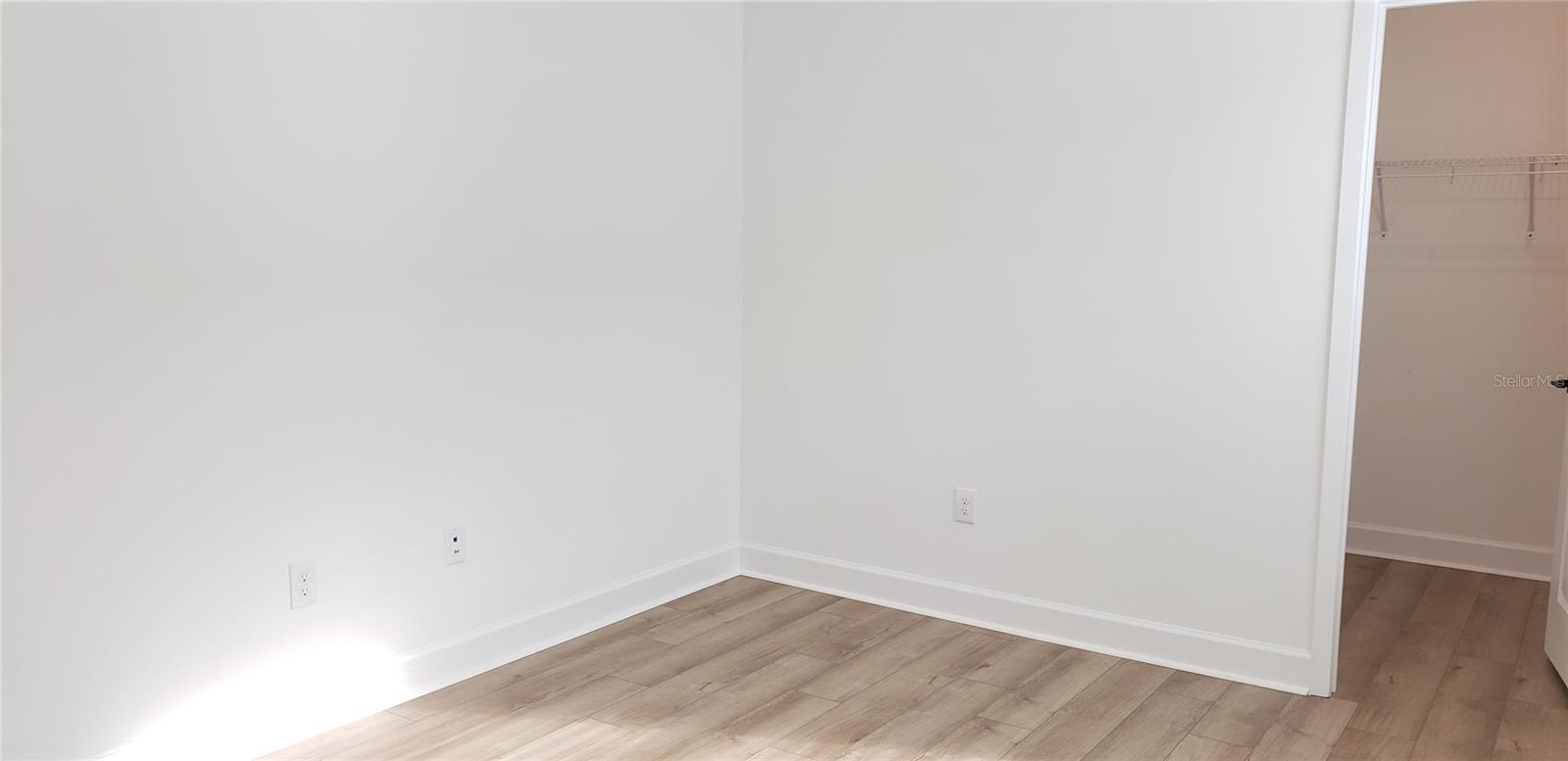 Empty room with light wood-look flooring and an open closet.