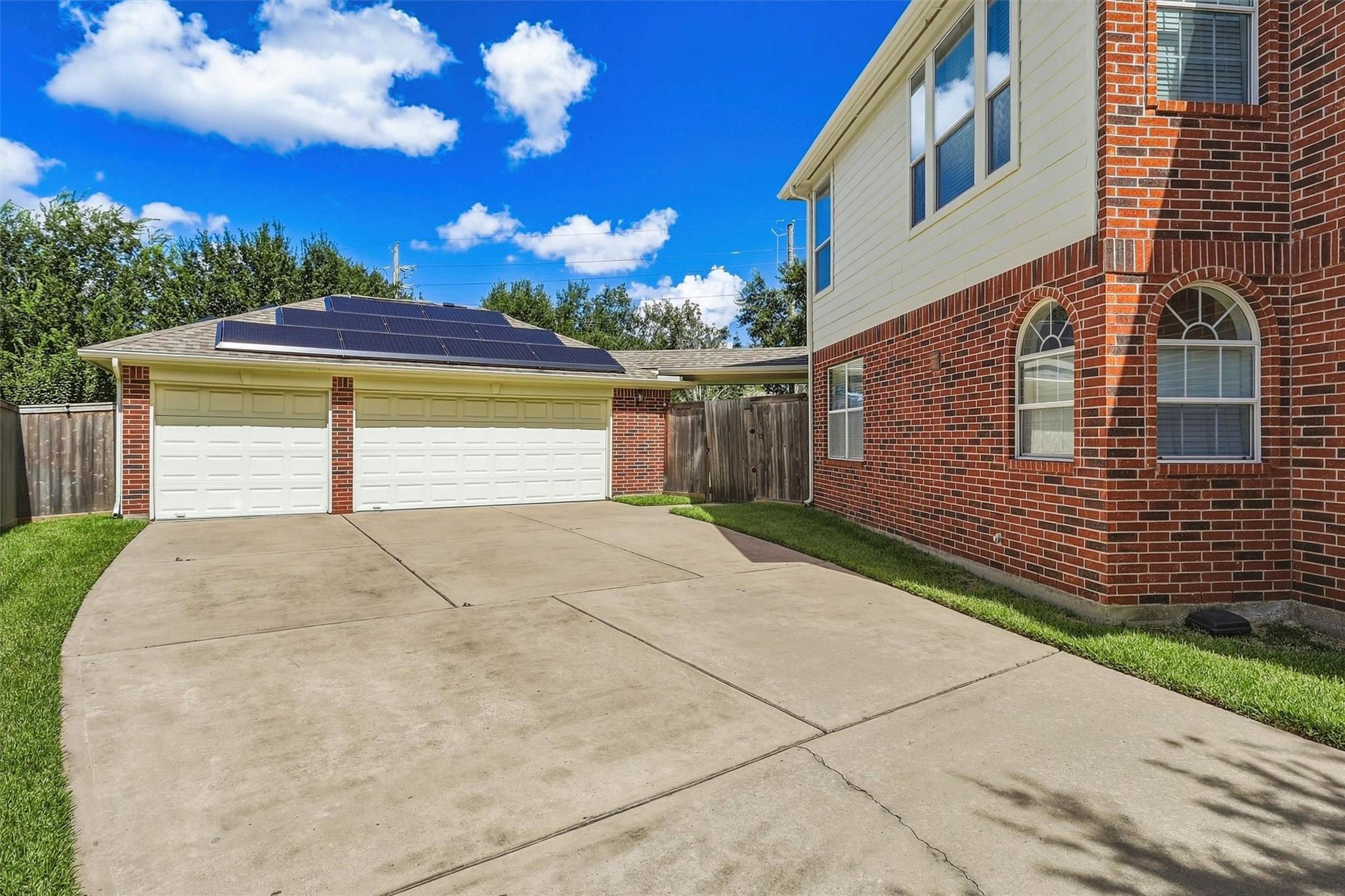 Home exterior with a wide driveway, double garage, and solar panels on the garage roof.