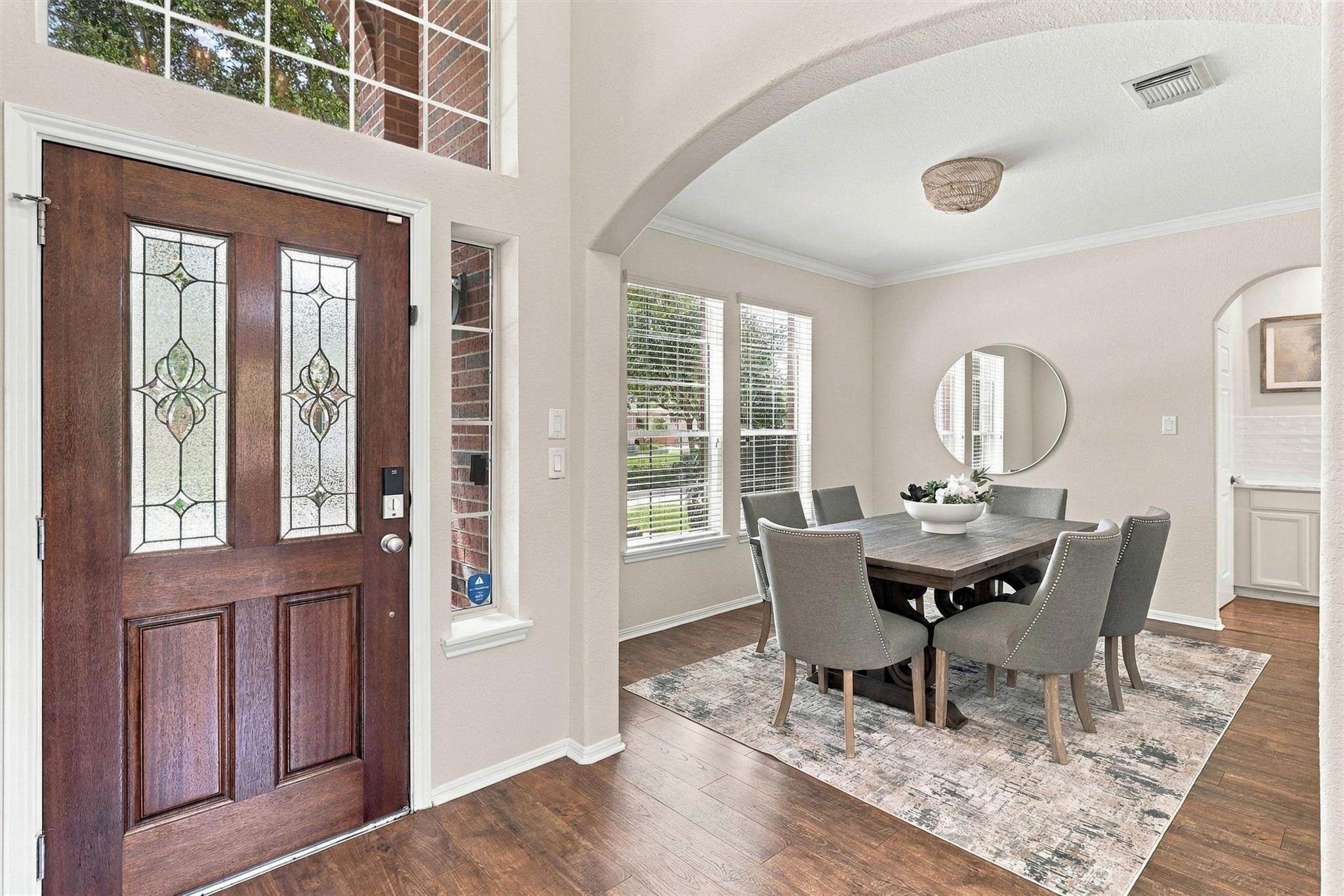 Entryway and dining room with a decorative glass front door and a gray-chair dining set.