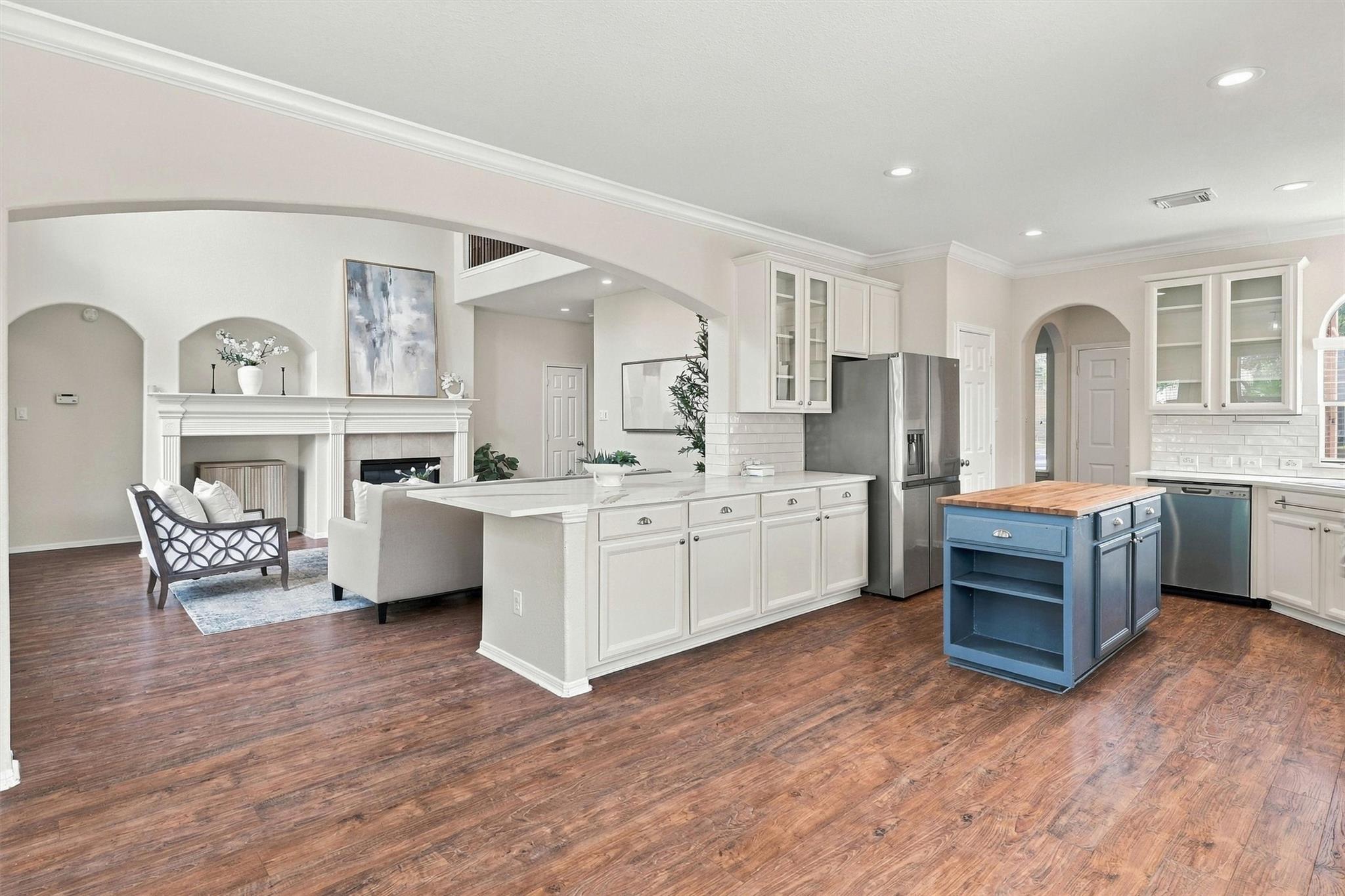 Open kitchen with a blue butcher-block island, white cabinetry, and an adjoining living area with a fireplace.