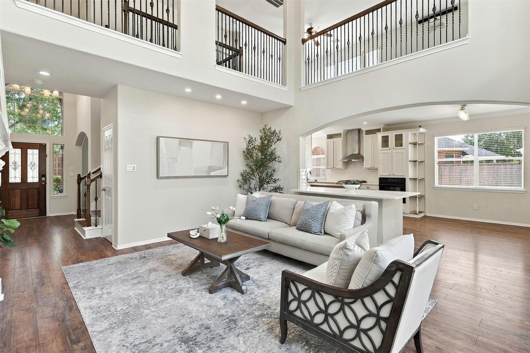 Open-plan living room with a double-height ceiling, furnished seating area, and white kitchen island.