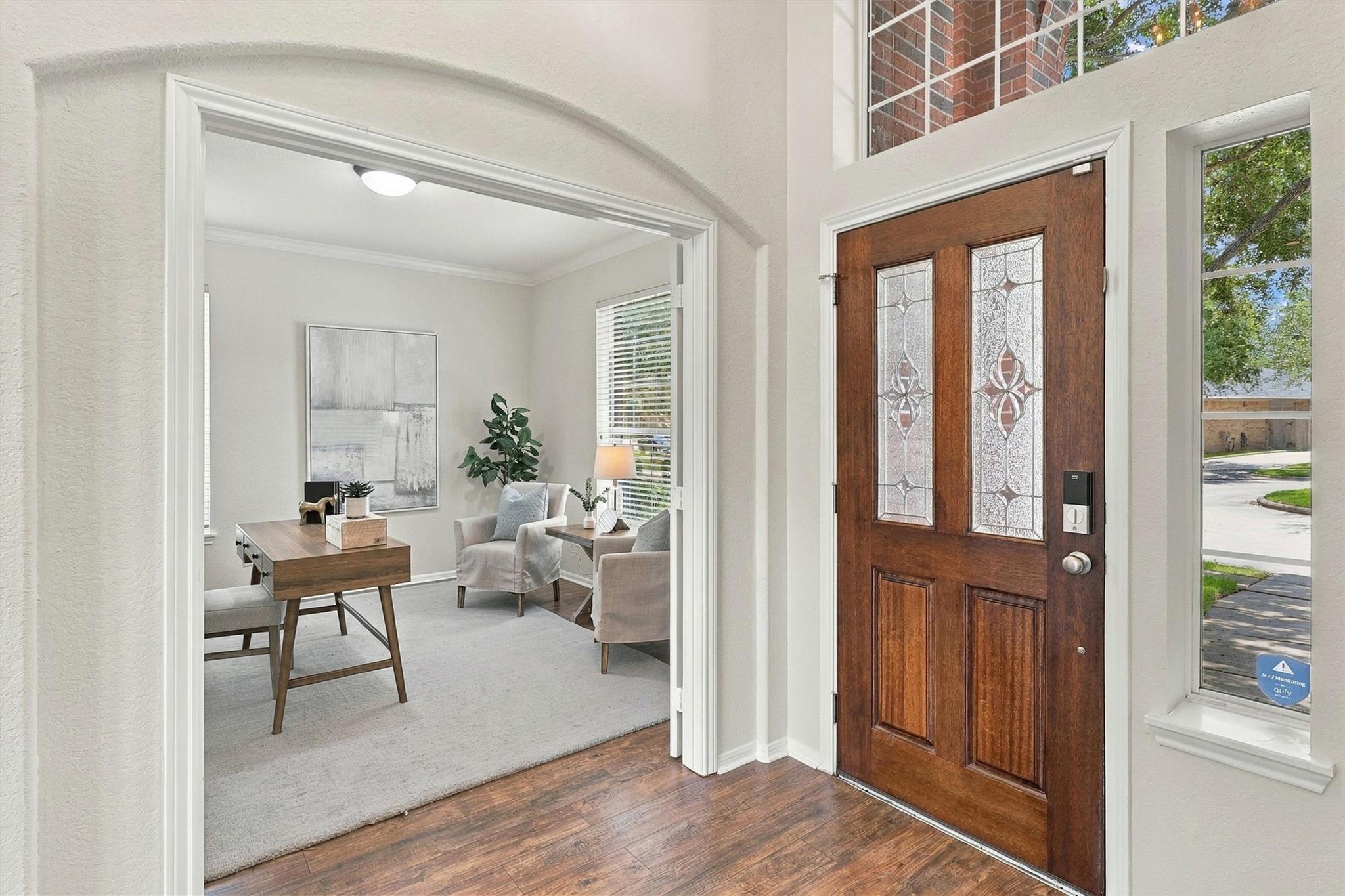 Home entryway with a decorative wood front door and a staged study visible through the doorway.