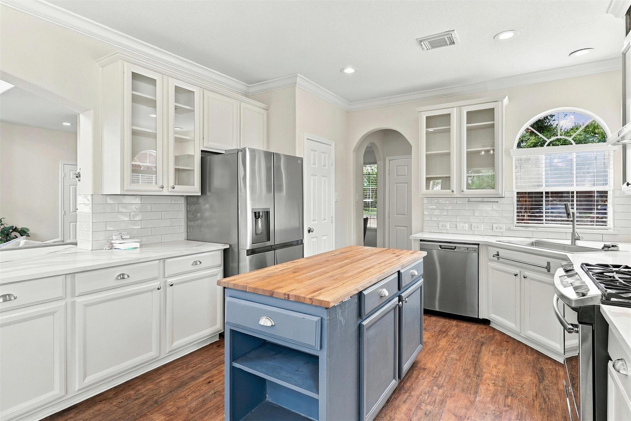 Kitchen with blue butcher-block island, white cabinets, and stainless steel appliances.
