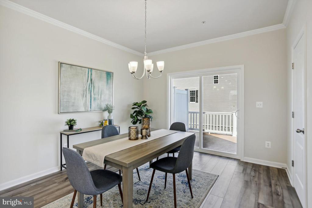 Dining room with a wood table and gray chairs beside sliding doors to a deck.