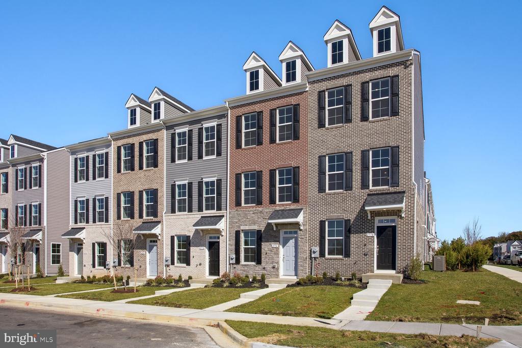 Attached three-story townhouses with brick and gray siding, peaked dormers, and small front lawns.