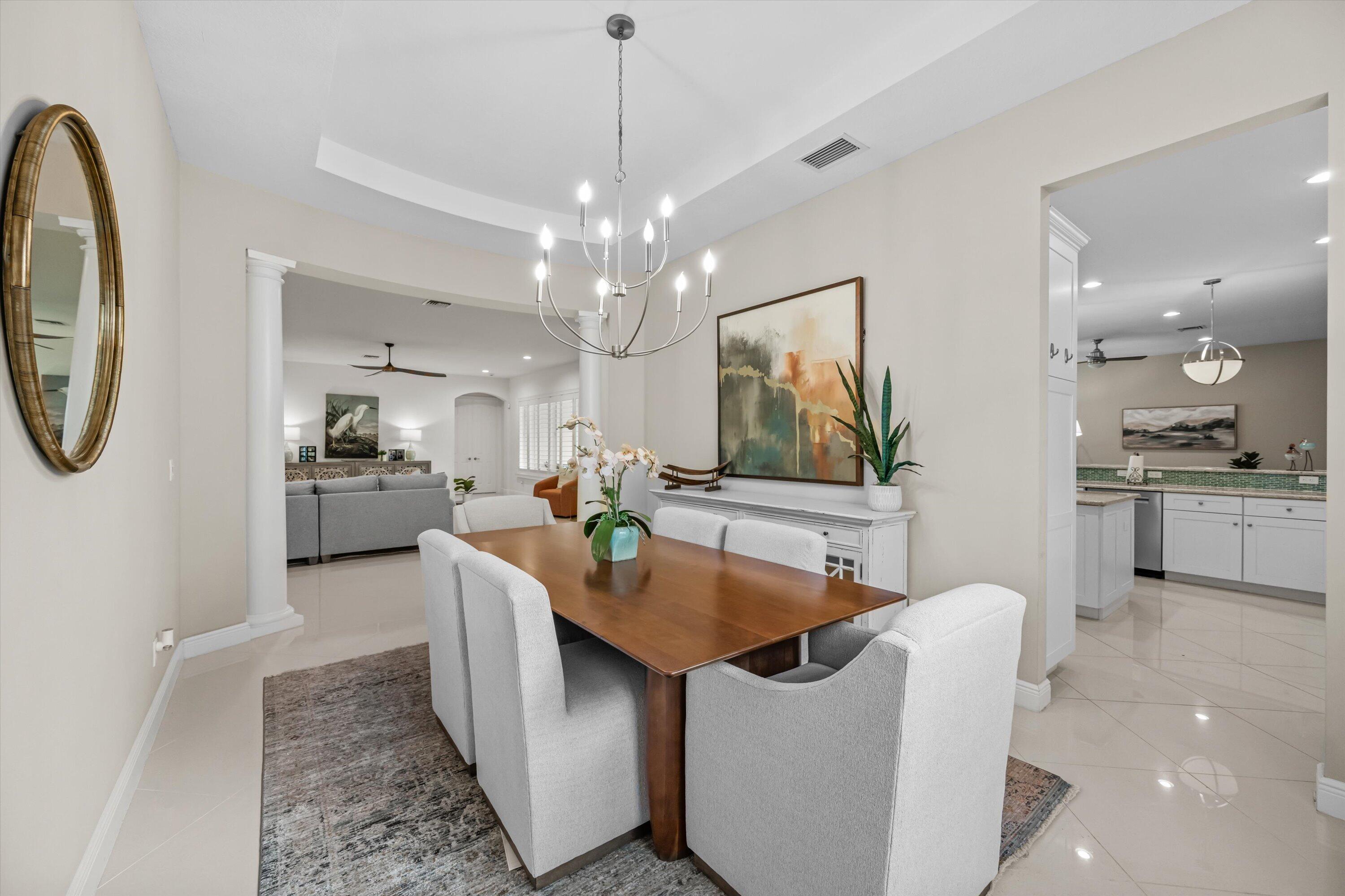 Dining room with a wood table and chandelier, opening to a living room and kitchen.
