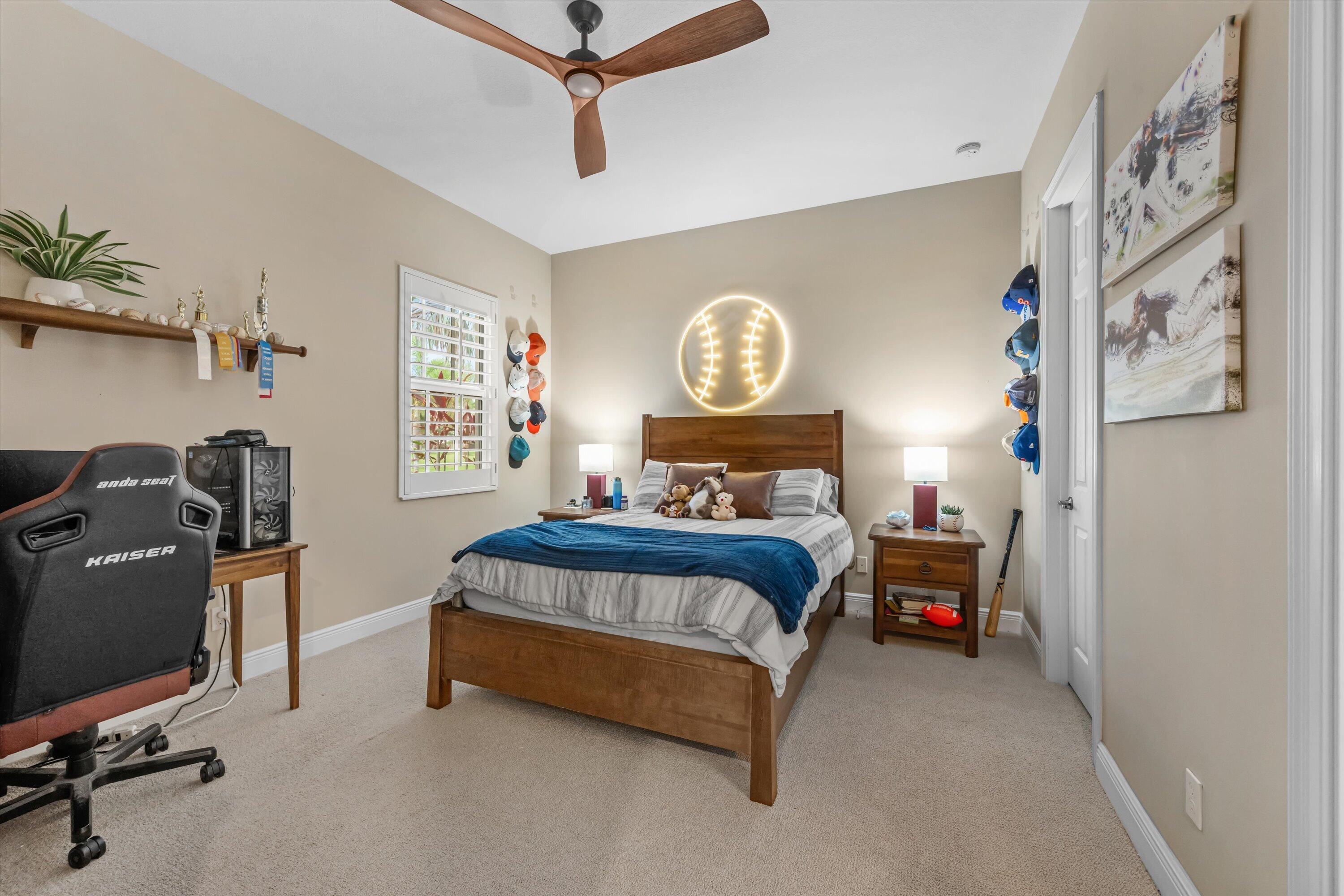 Bedroom with a wooden bed, glowing baseball wall light, and gaming setup.