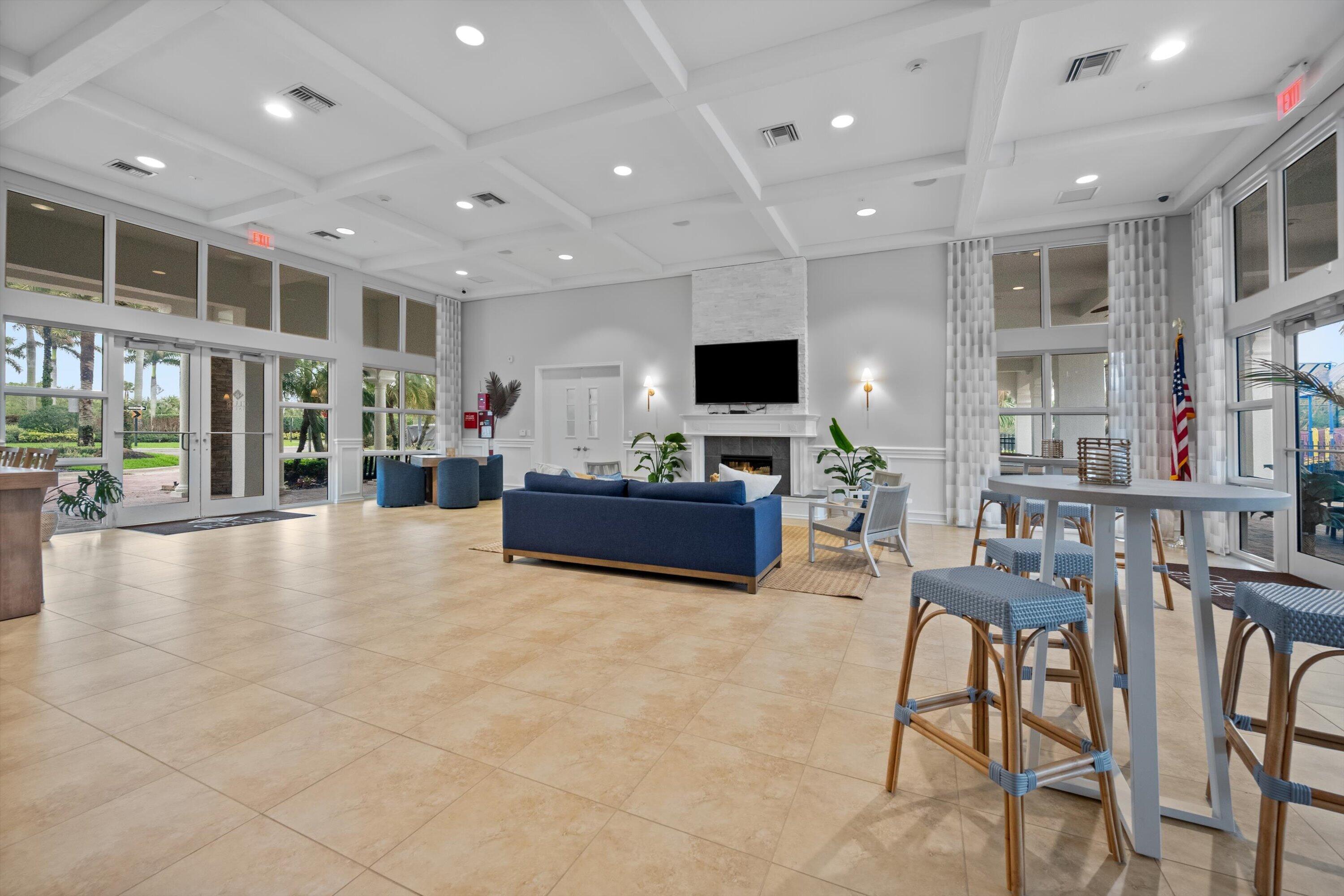 Community lounge with blue seating, a fireplace, and tall windows.
