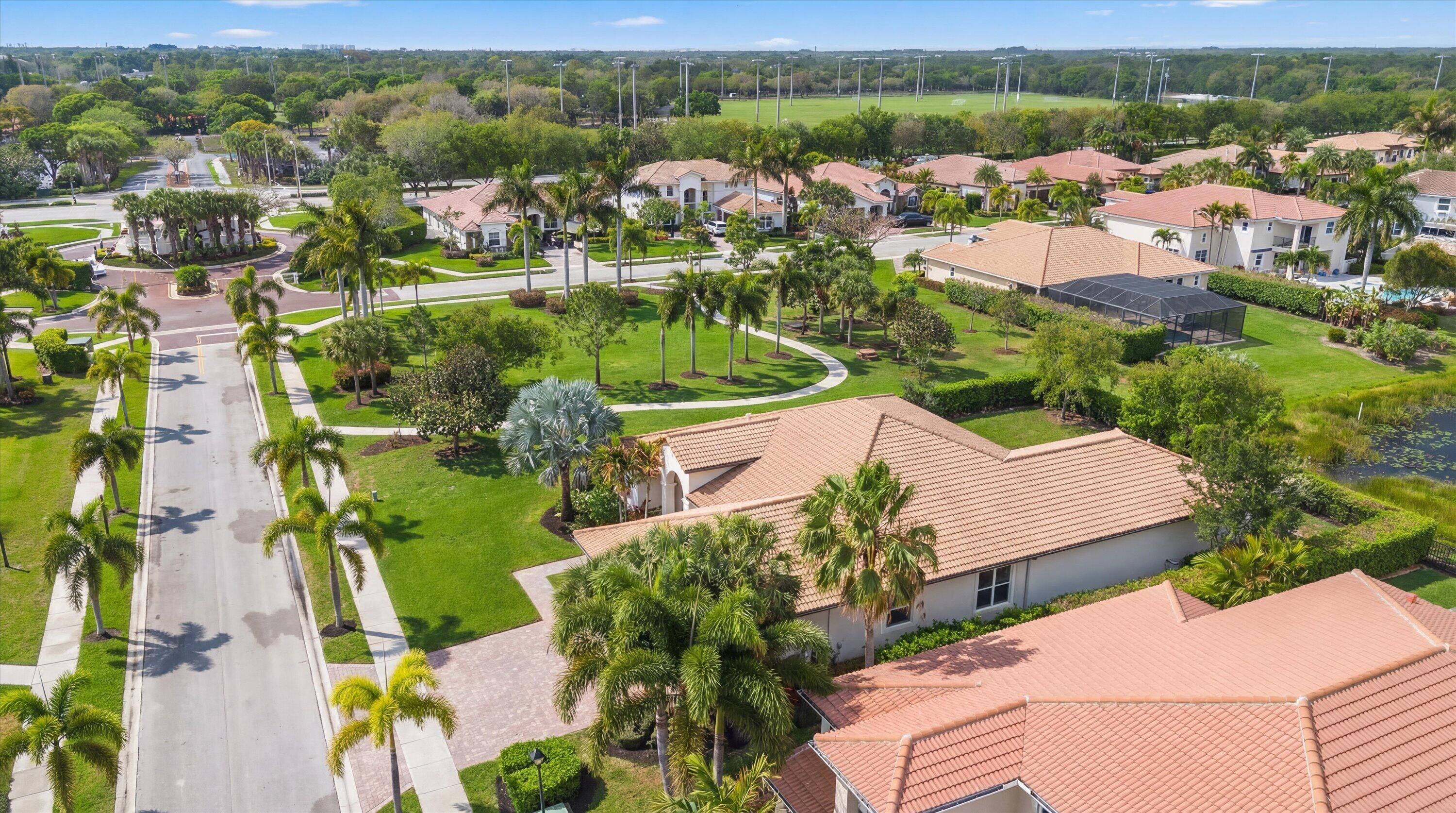Aerial view of a tile-roofed home and palm-lined neighborhood streets.