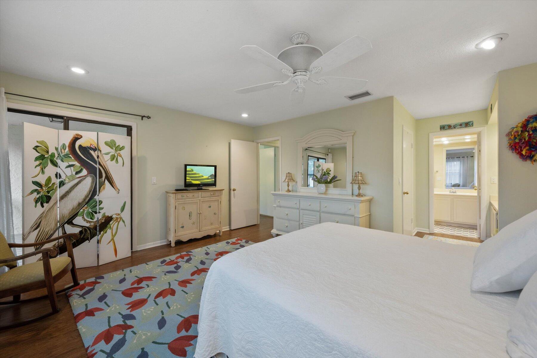 Bedroom with a white bed, colorful rug, and pelican-painted folding screen