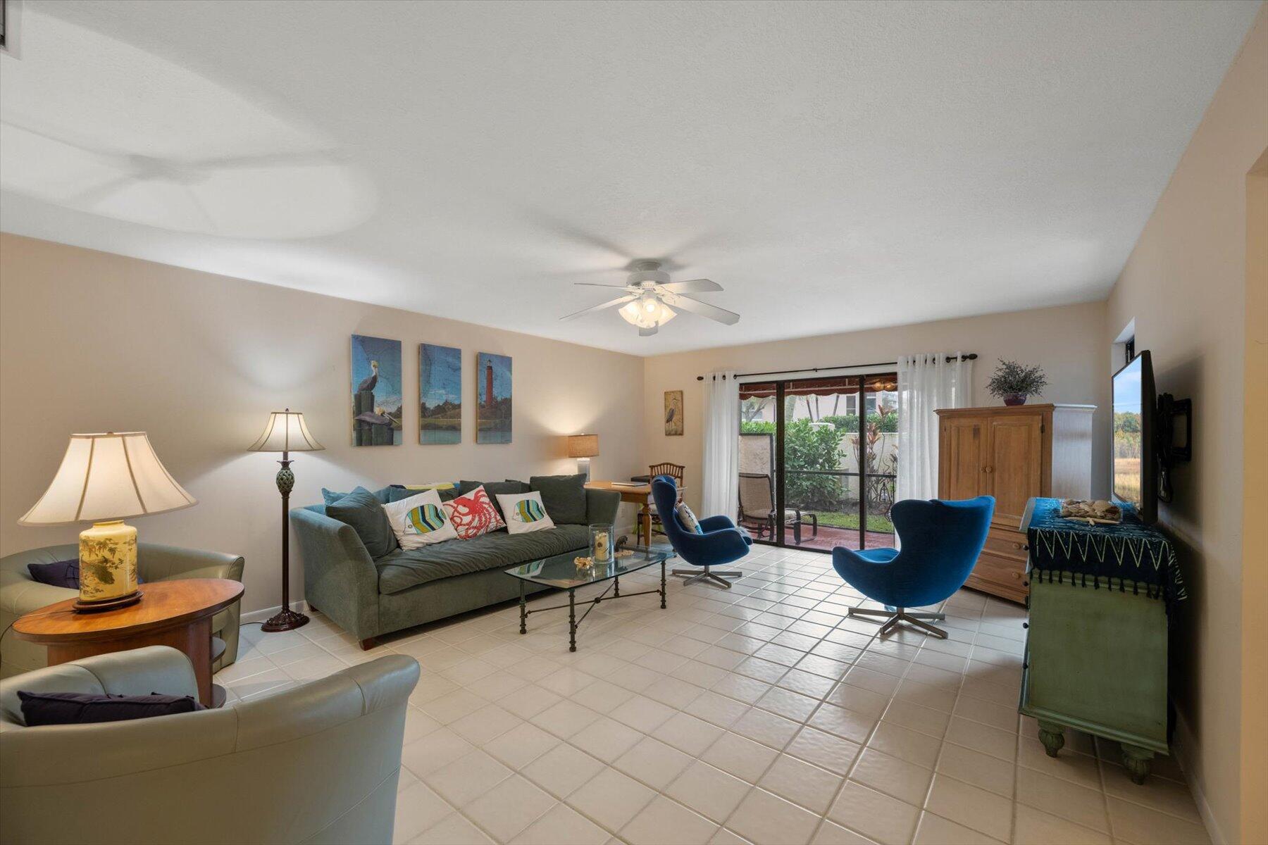 Furnished living room with blue accent chairs and sliding glass doors opening to a patio.