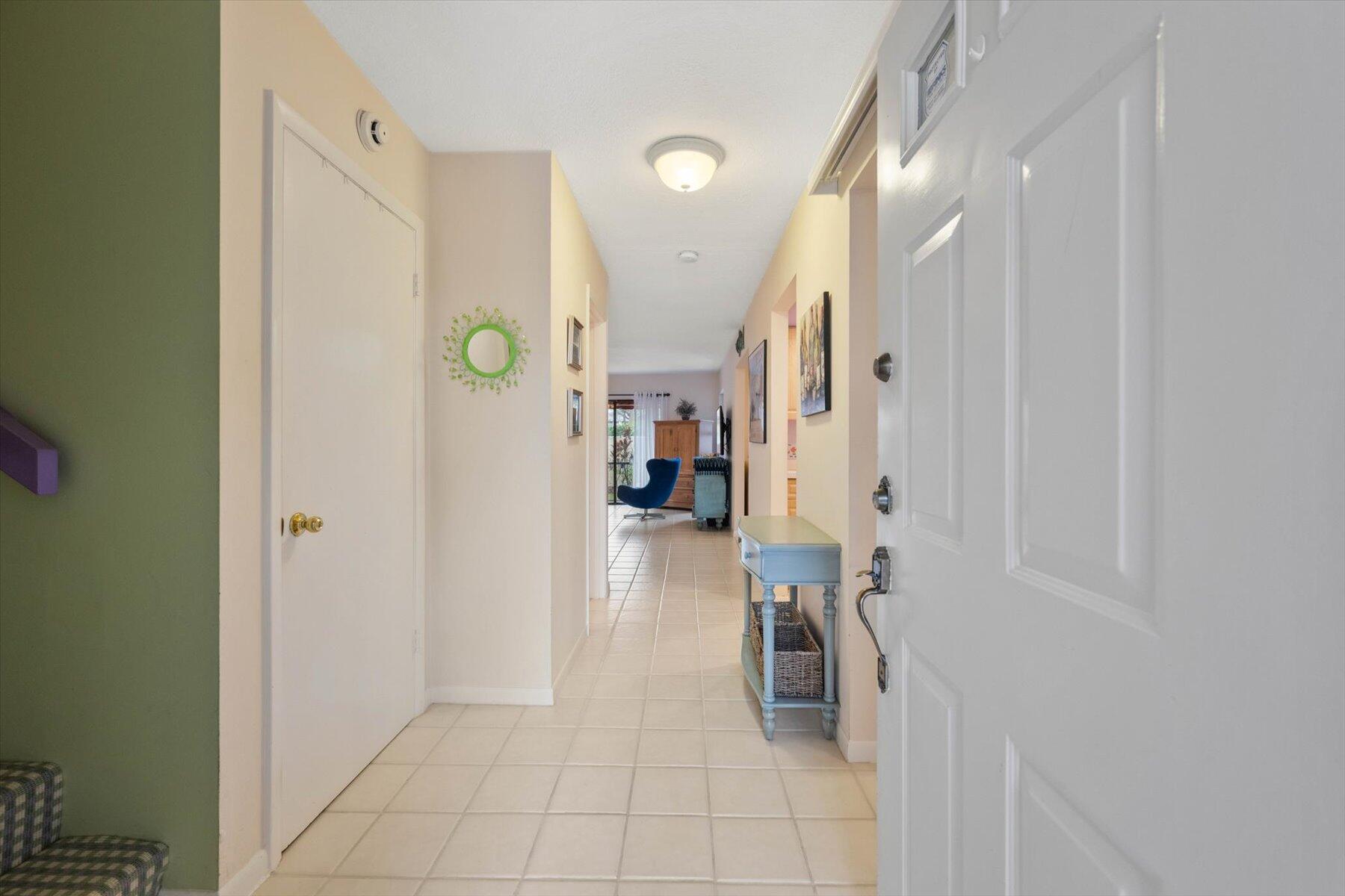 Condo entry hallway with pale tile floors and a light blue console table beside the front door.