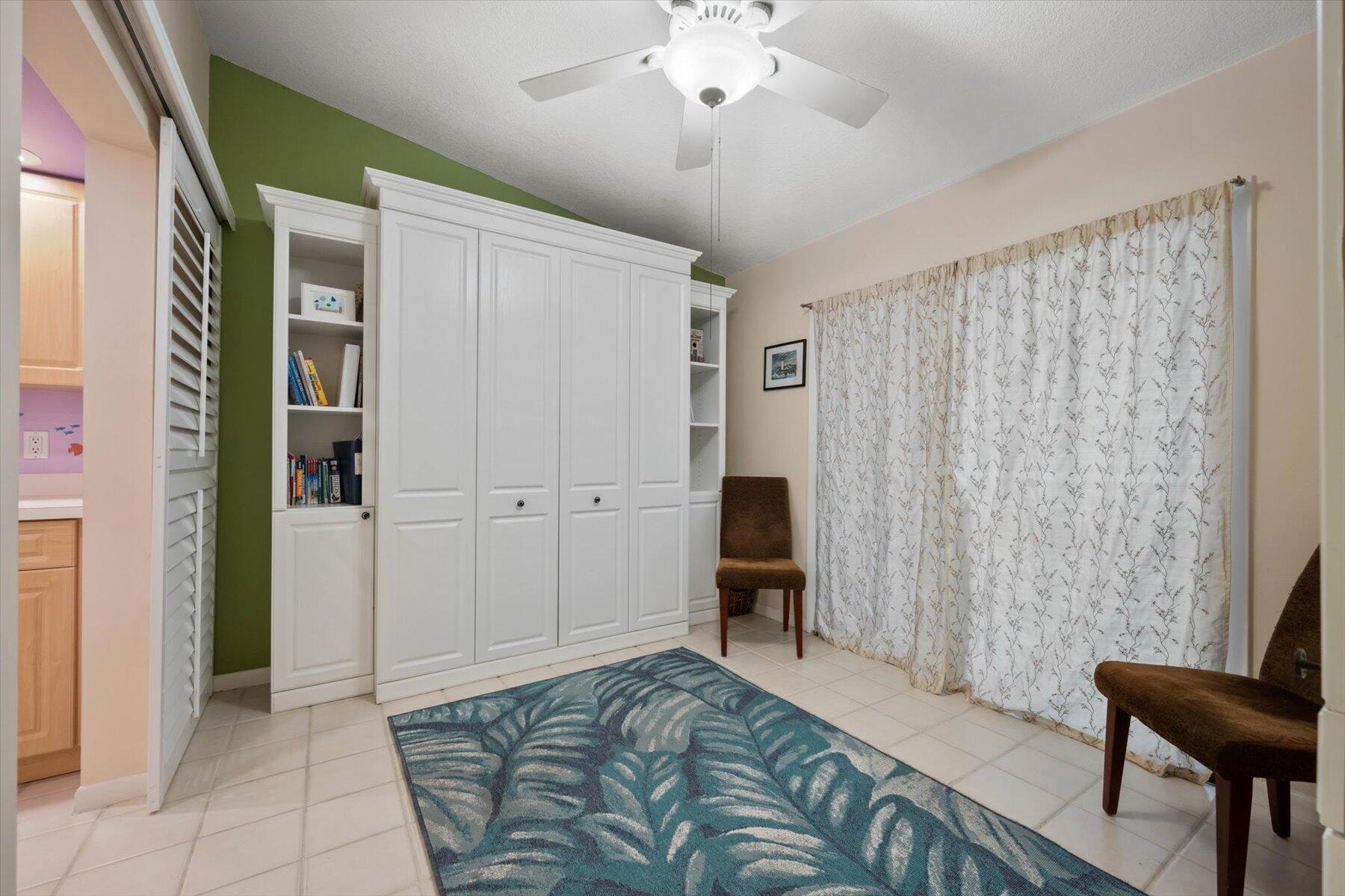 Room with white built-in cabinets, patterned curtains, and a blue area rug