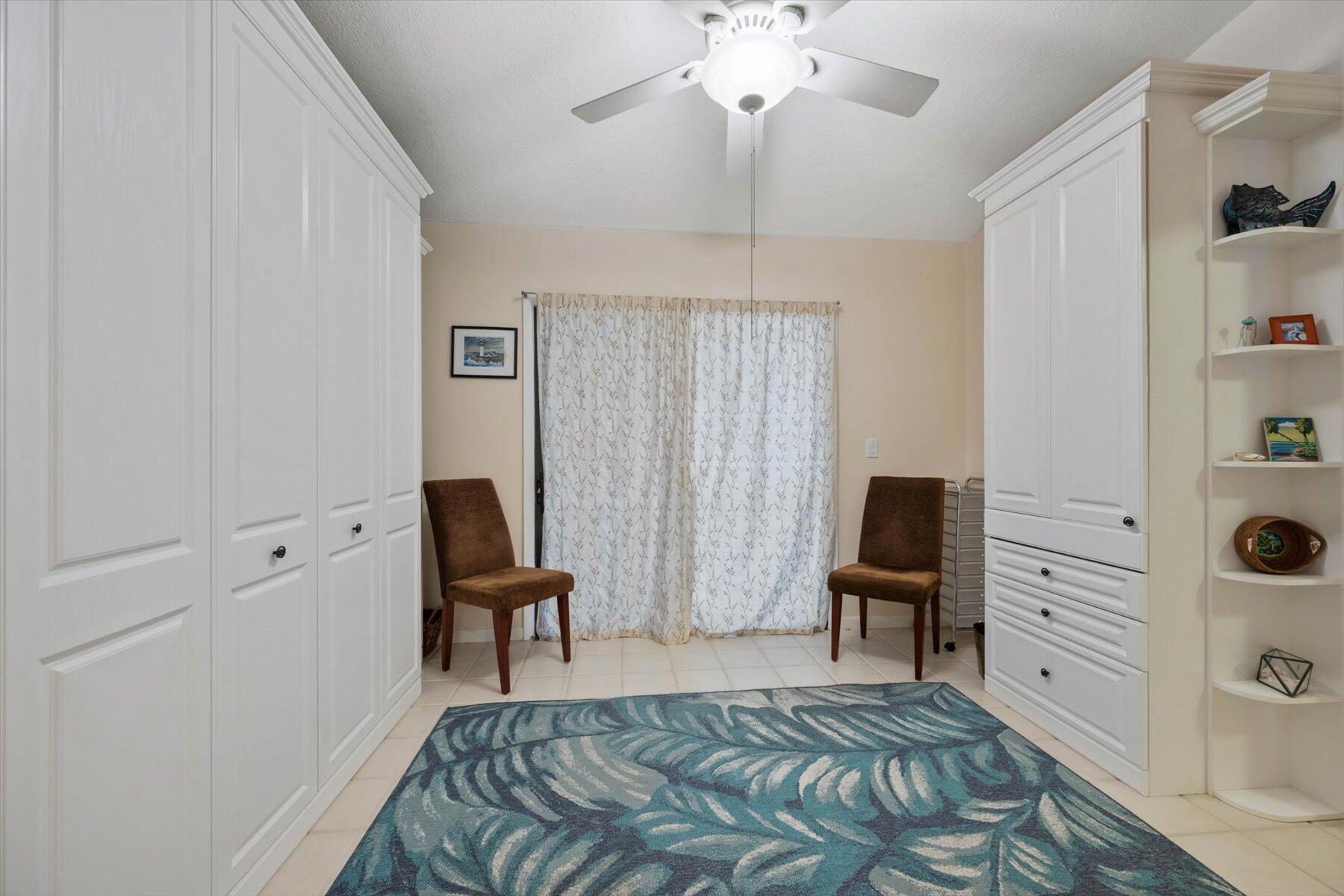 Dressing room with white built-in wardrobes, two brown chairs, and a blue patterned rug.