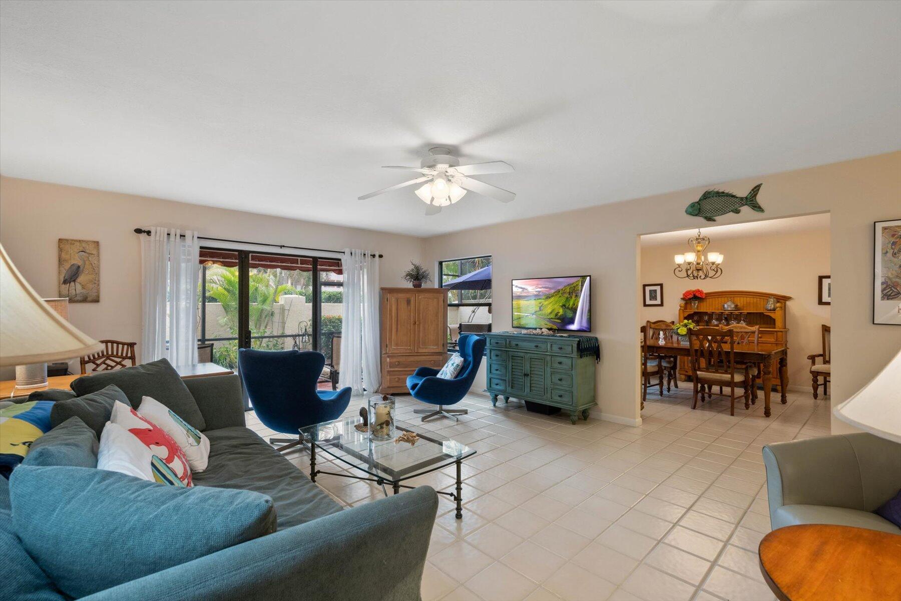 Living room with a blue sectional and accent chairs beside sliding glass doors to a landscaped patio.