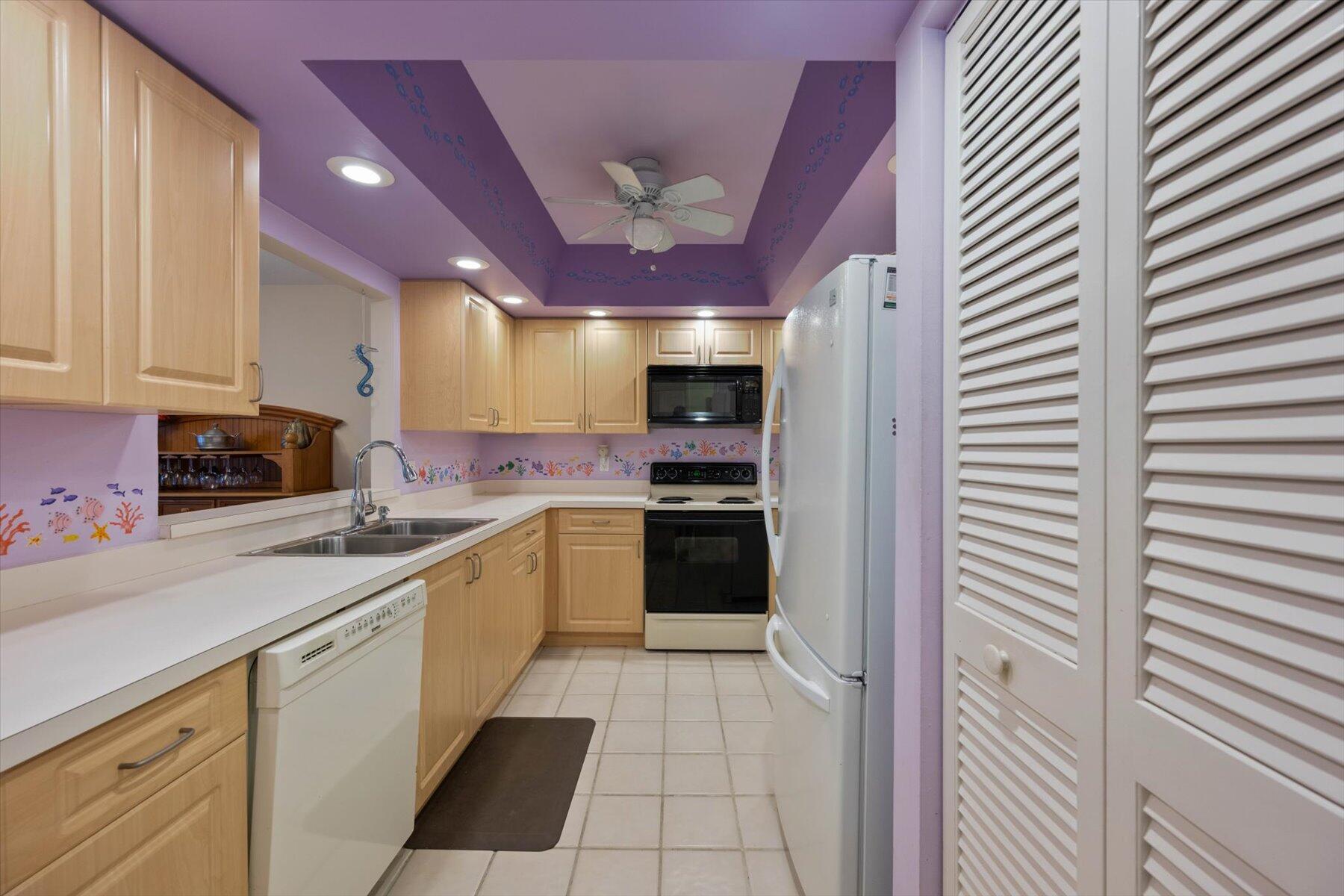 Kitchen with light wood cabinets, white countertops, and distinctive purple walls and ceiling.
