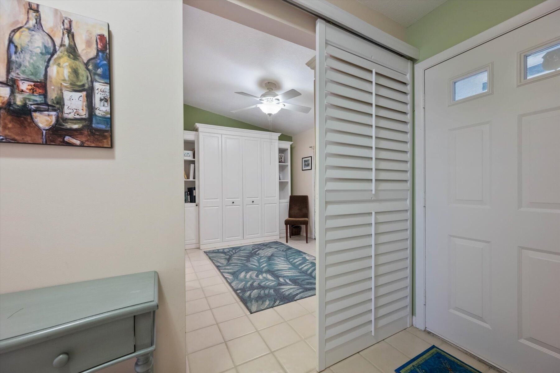 Tiled entryway with a white louvered closet door, built-in cabinets, and a blue patterned rug.