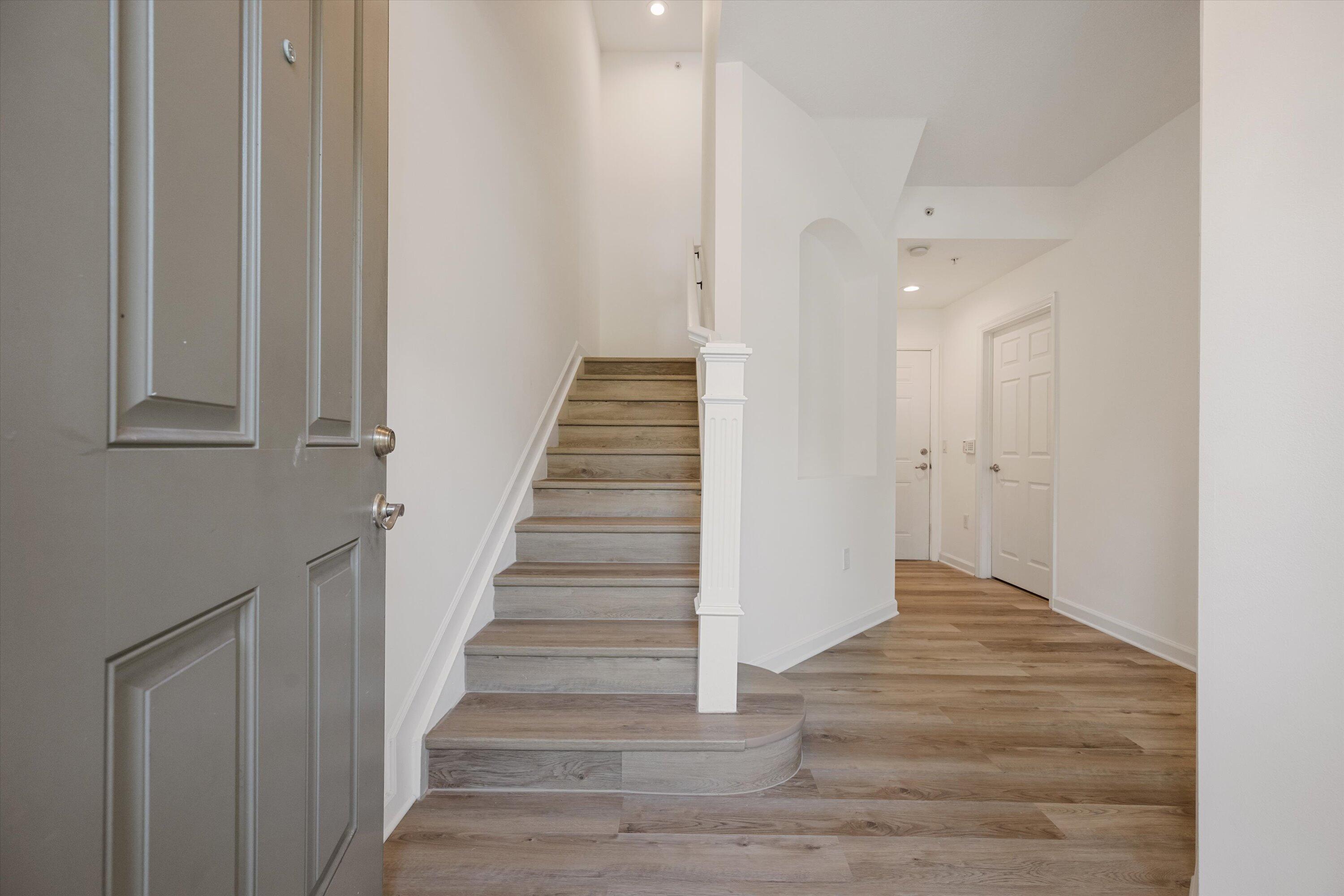 Entry foyer with a gray front door, wood-look floors, and a staircase.