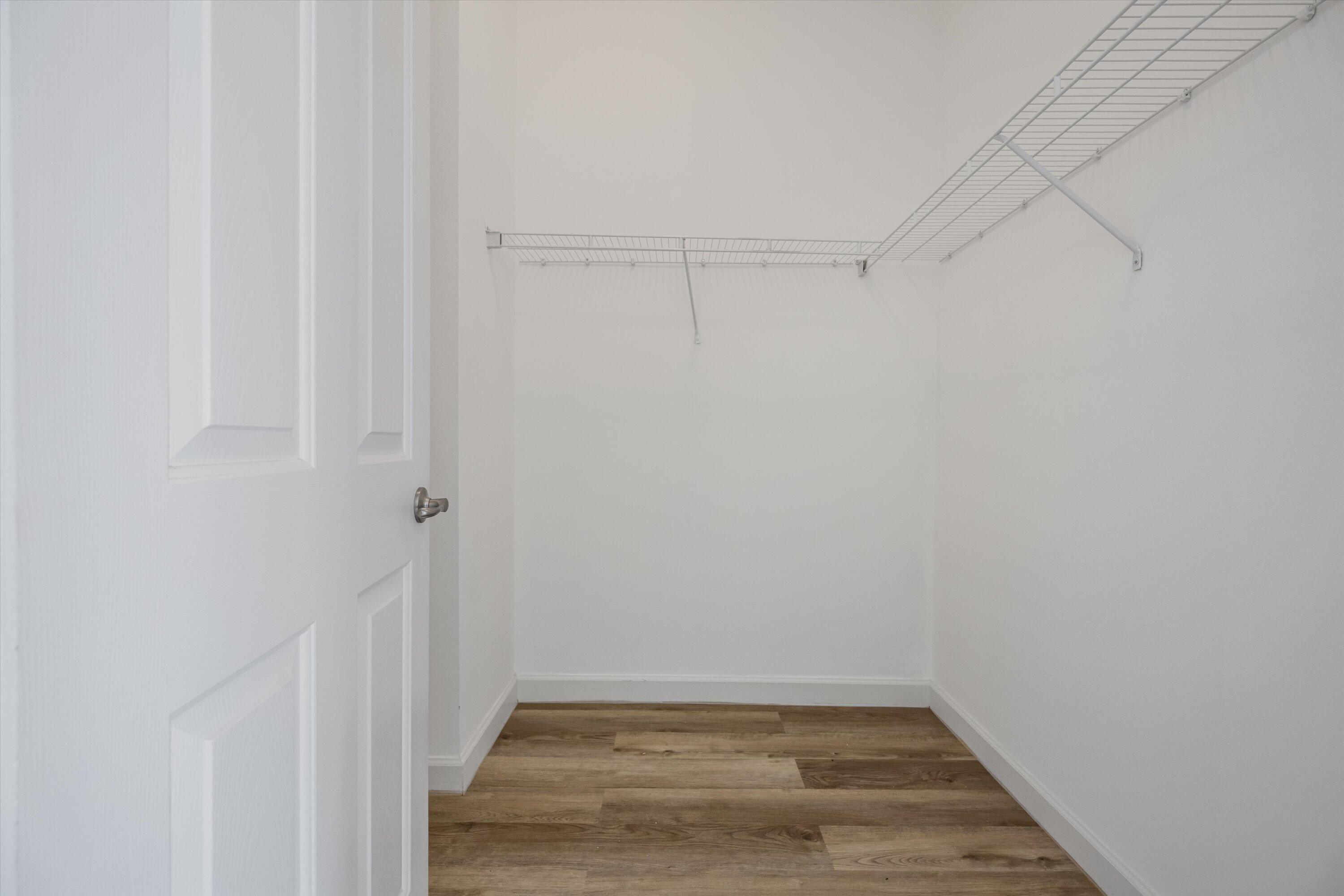 Empty walk-in closet with white wire shelving and wood-look plank flooring.
