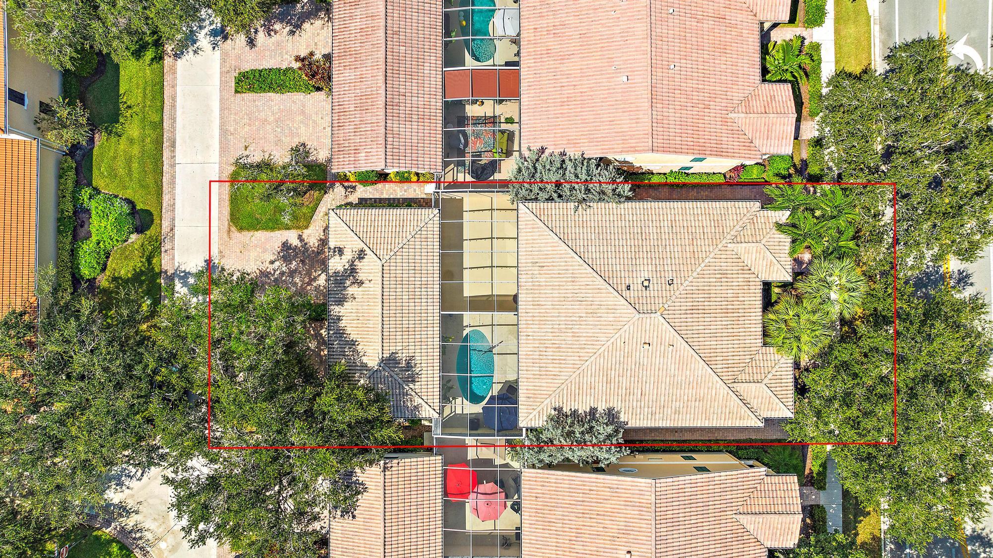 Aerial view of a tile-roofed home with a glass-enclosed courtyard and pool, outlined in red.