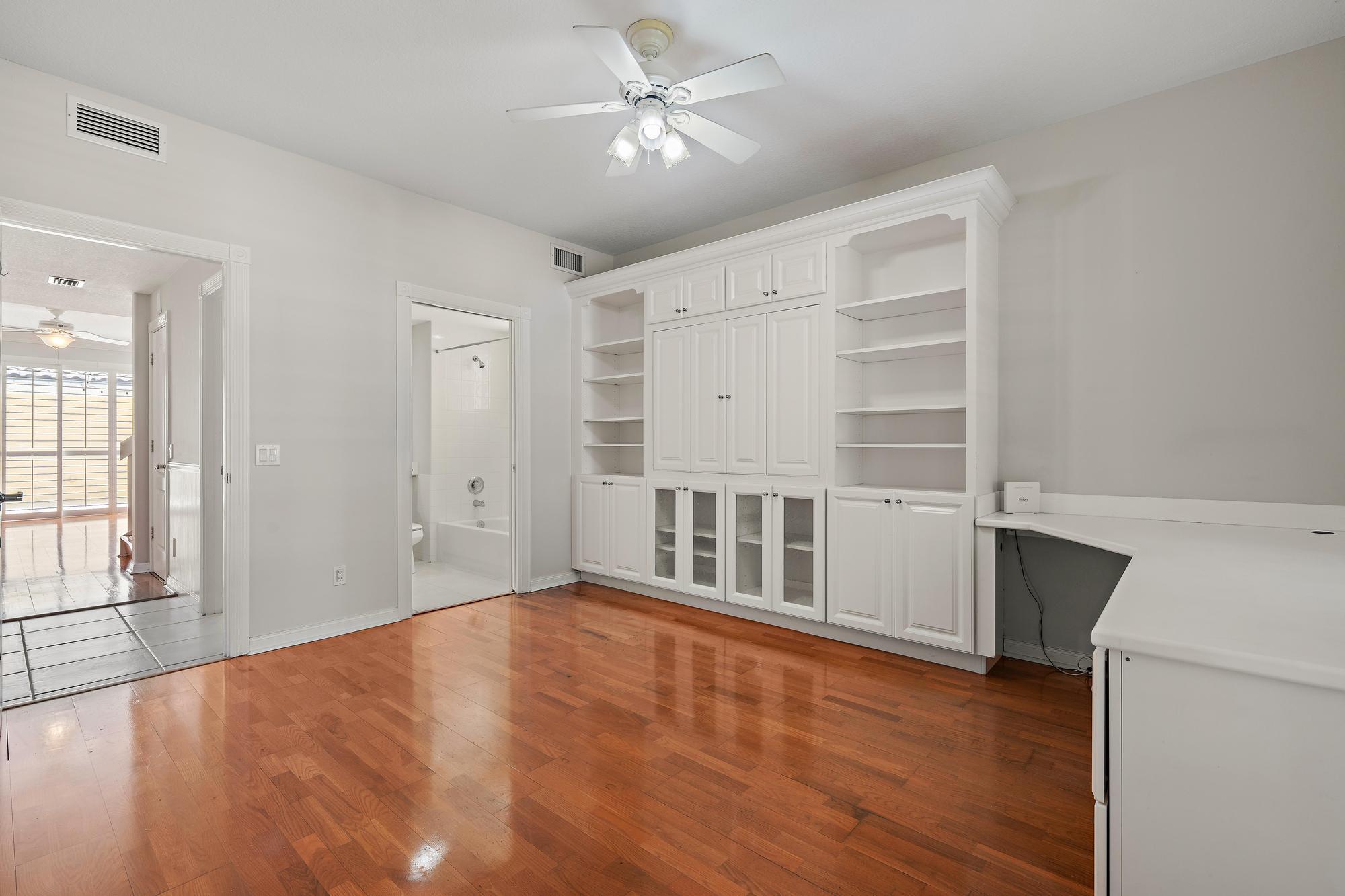 Interior room with hardwood floors and extensive white built-in cabinetry and shelving.