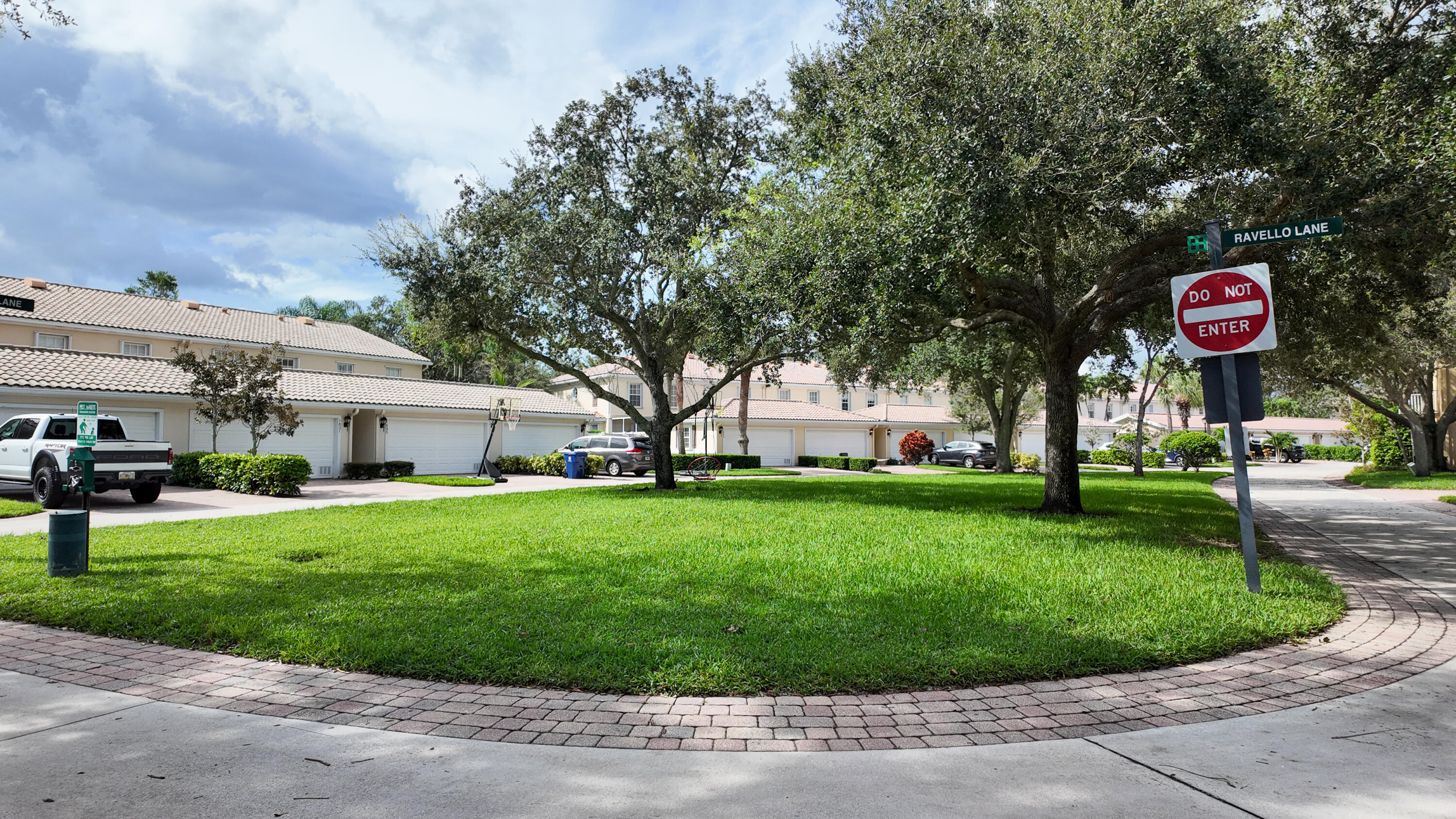 Residential street with tiled-roof homes, mature shade trees, and a Ravello Lane sign.