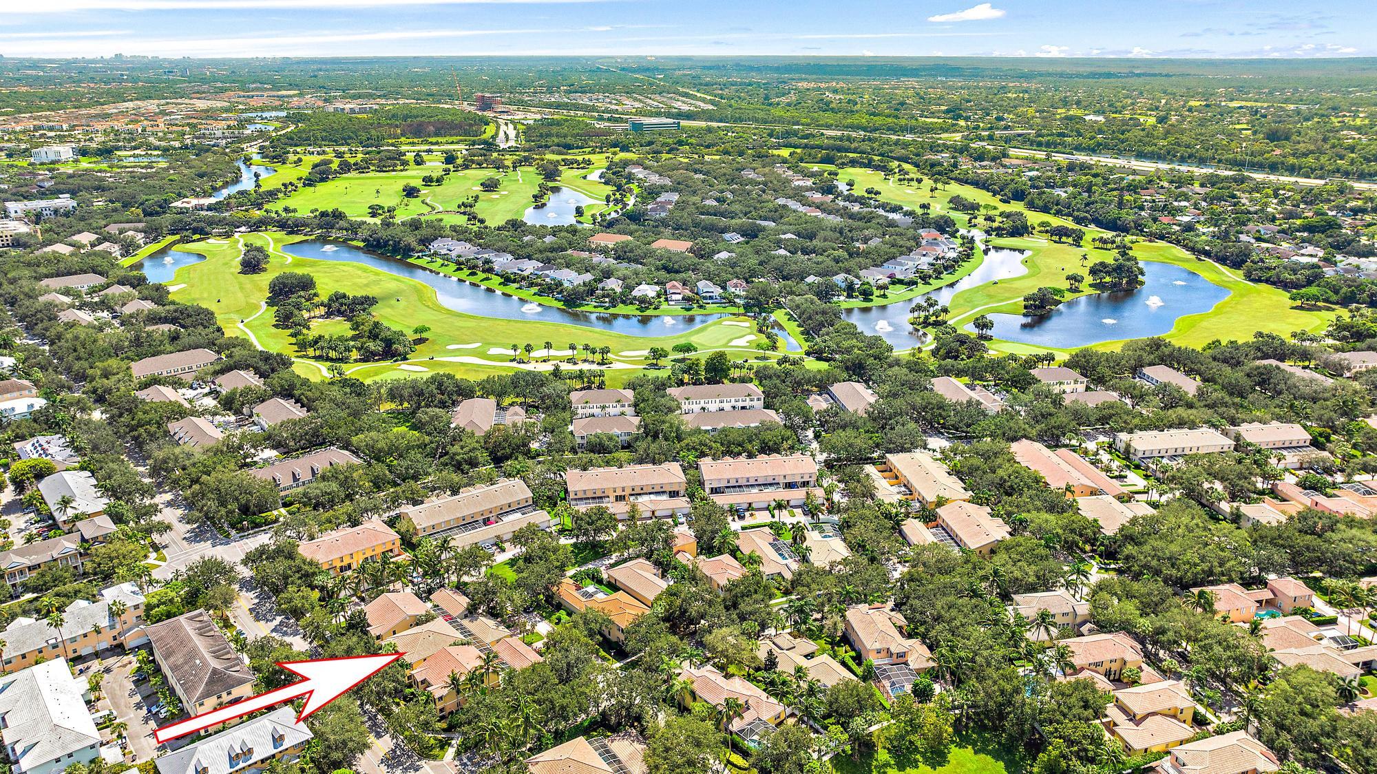 Aerial view of a residential community beside a golf course, with an arrow marking the property.