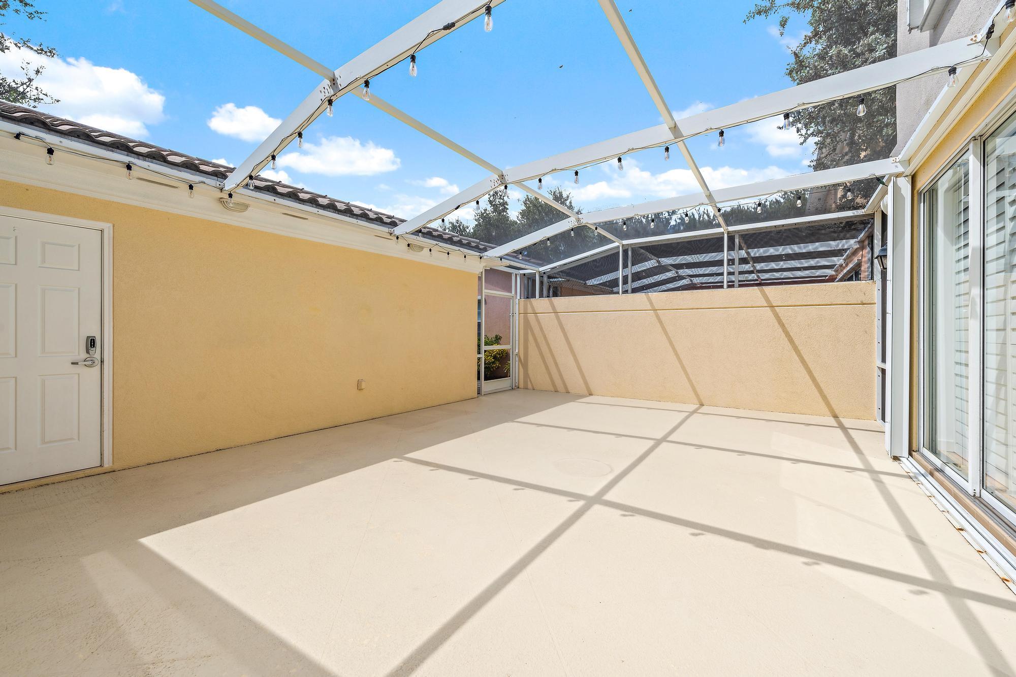 Screened patio with a translucent roof, string lights, and sliding glass doors.