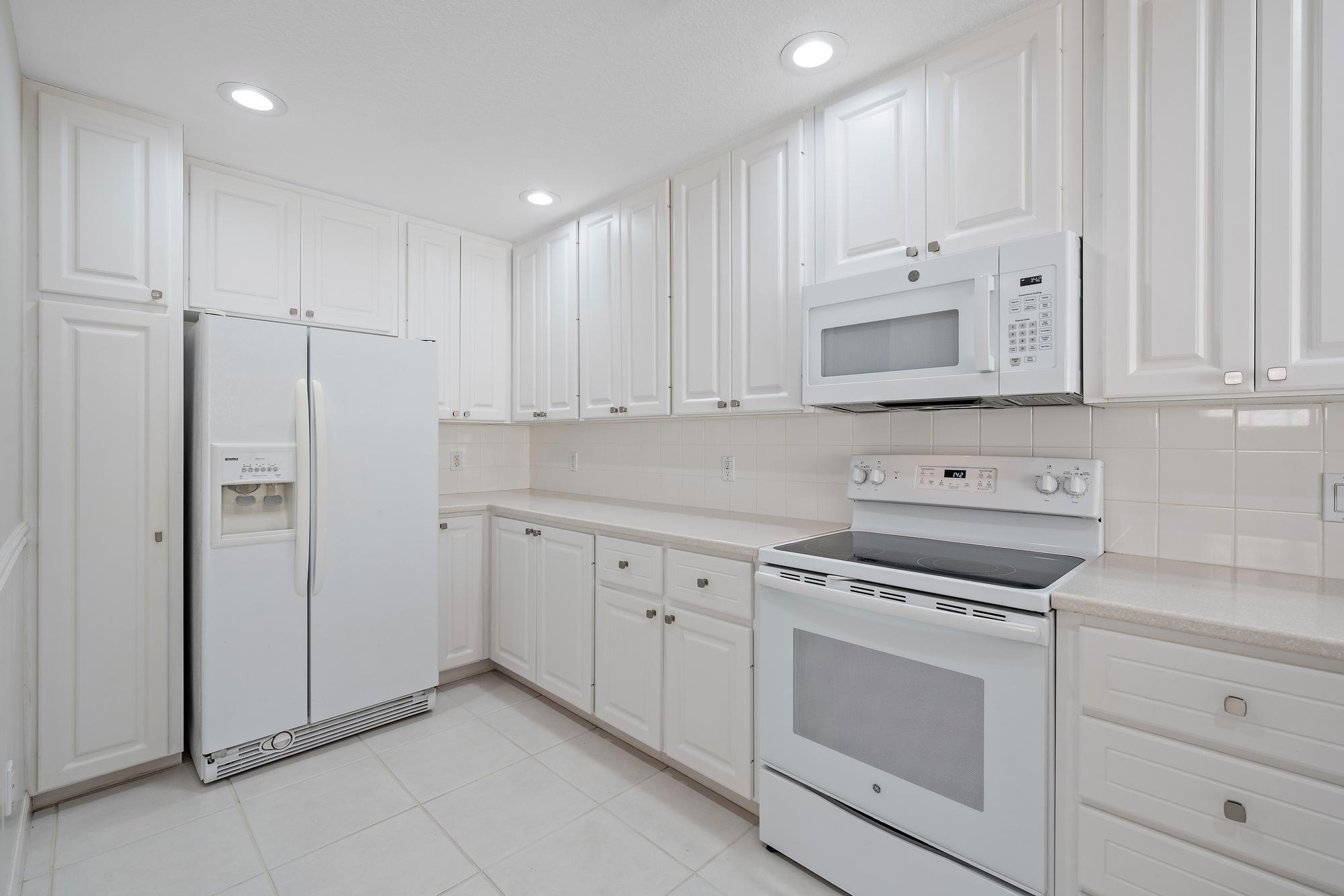 Kitchen with white cabinets, refrigerator, electric range, and over-the-range microwave.