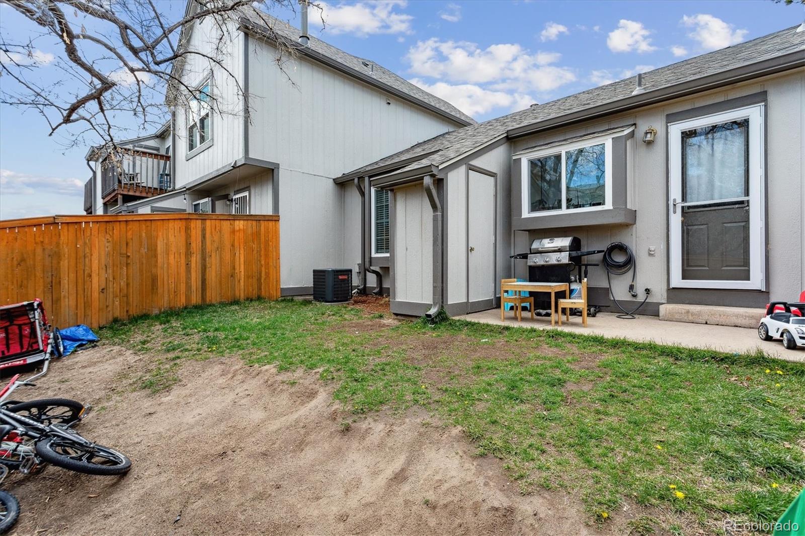 Townhouse rear exterior with a fenced yard, patio grill, and neighboring attached homes.